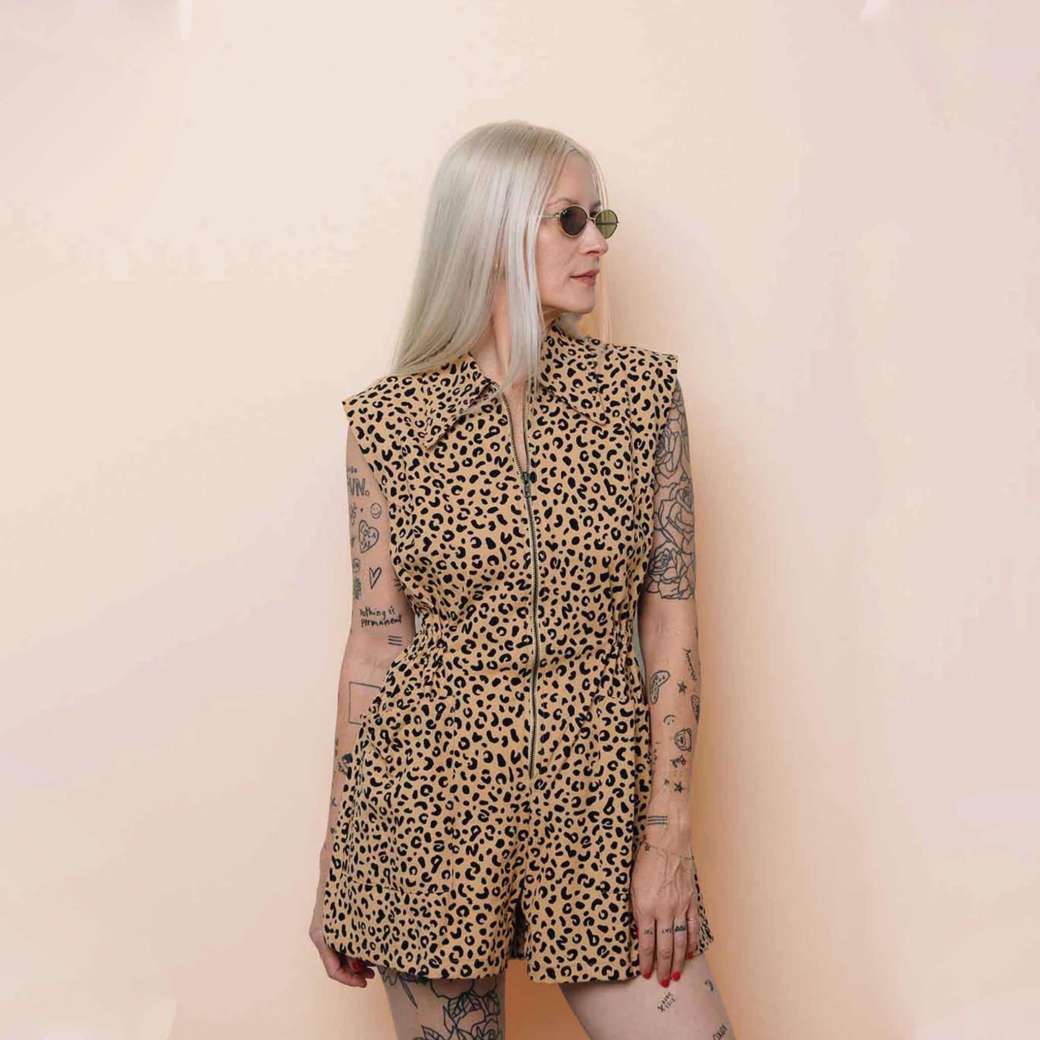 Person wearing a leopard print romper against a beige background