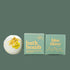 On a neutral background is a green bath bomb with a green box next to it that reads, "bath bomb enhanced with essential oils, clays & herbs"
