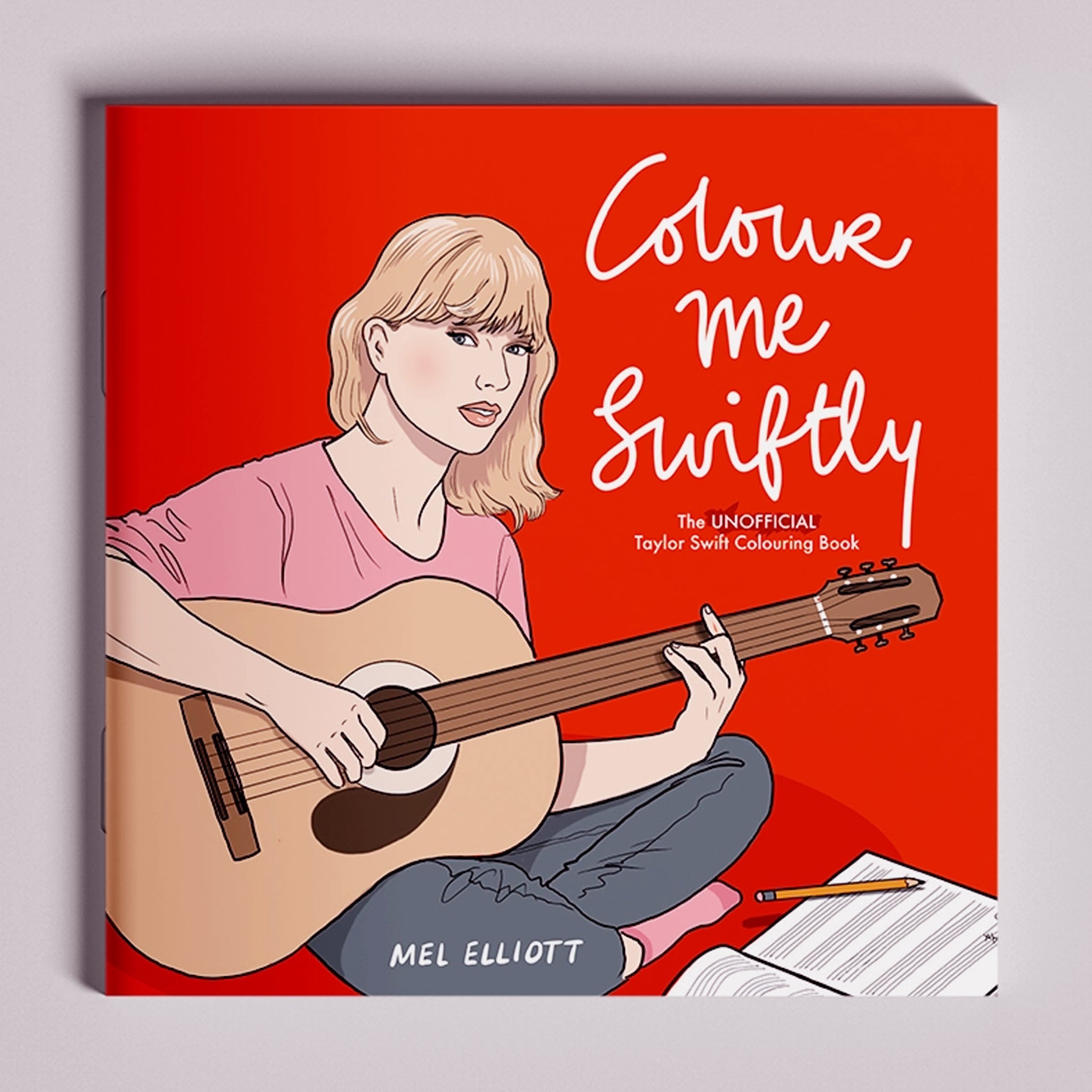On a grey background is a red book with an illustration of Taylor Swift with a guitar and the white title on the right that reads, &quot;Colour me Swiftly The Unofficial Taylor Swift Colouring Book&quot;. 