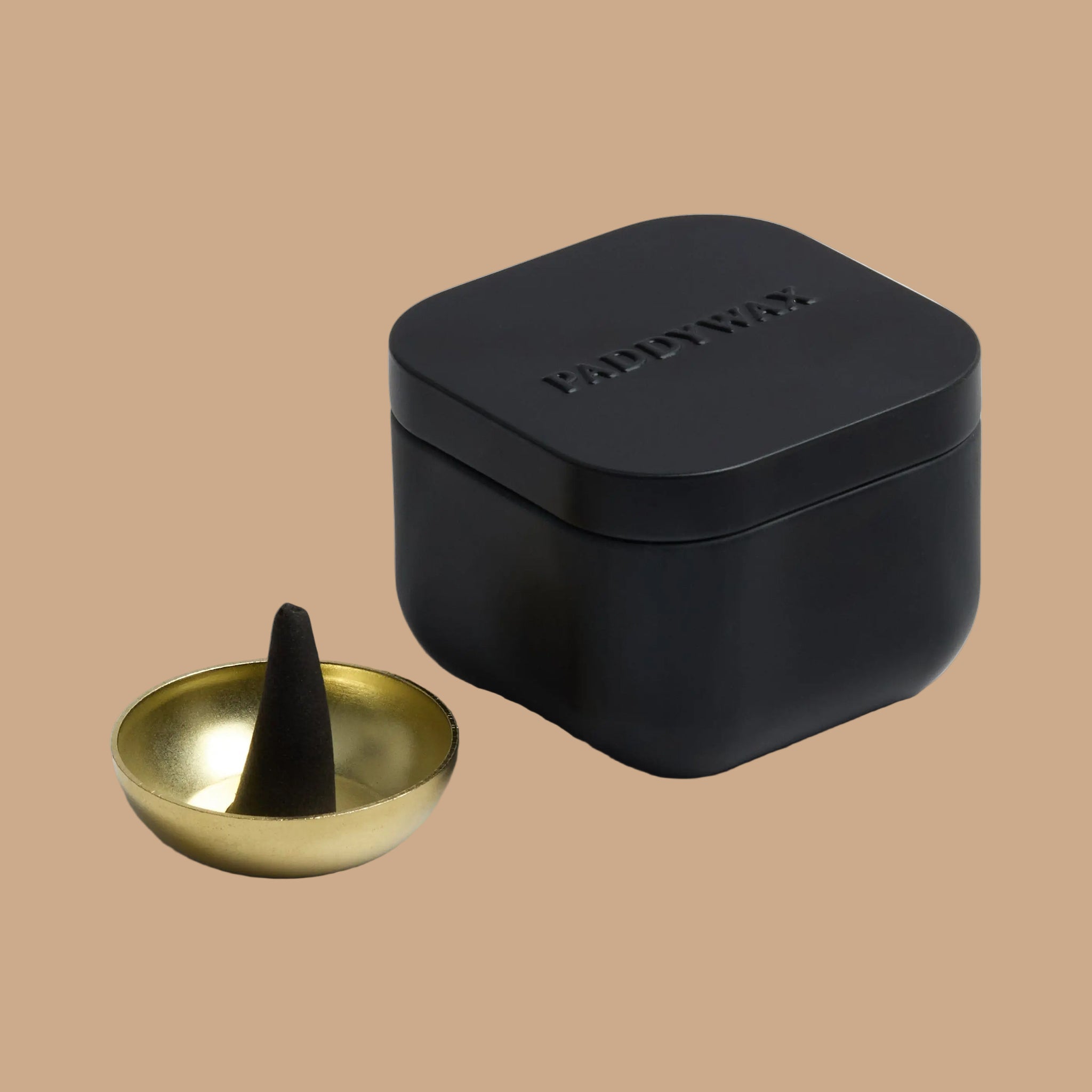 A black tin box filled with black cone incense and a gold small bowl. 