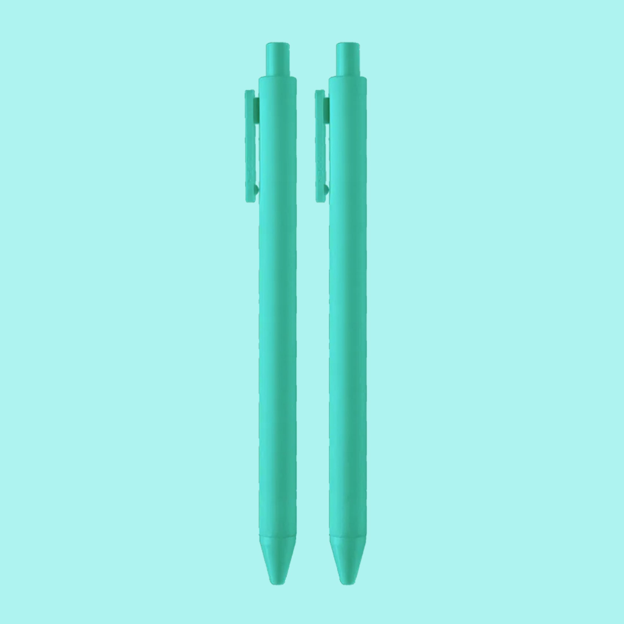 On a teal background is a teal pair of ballpoint pens. 