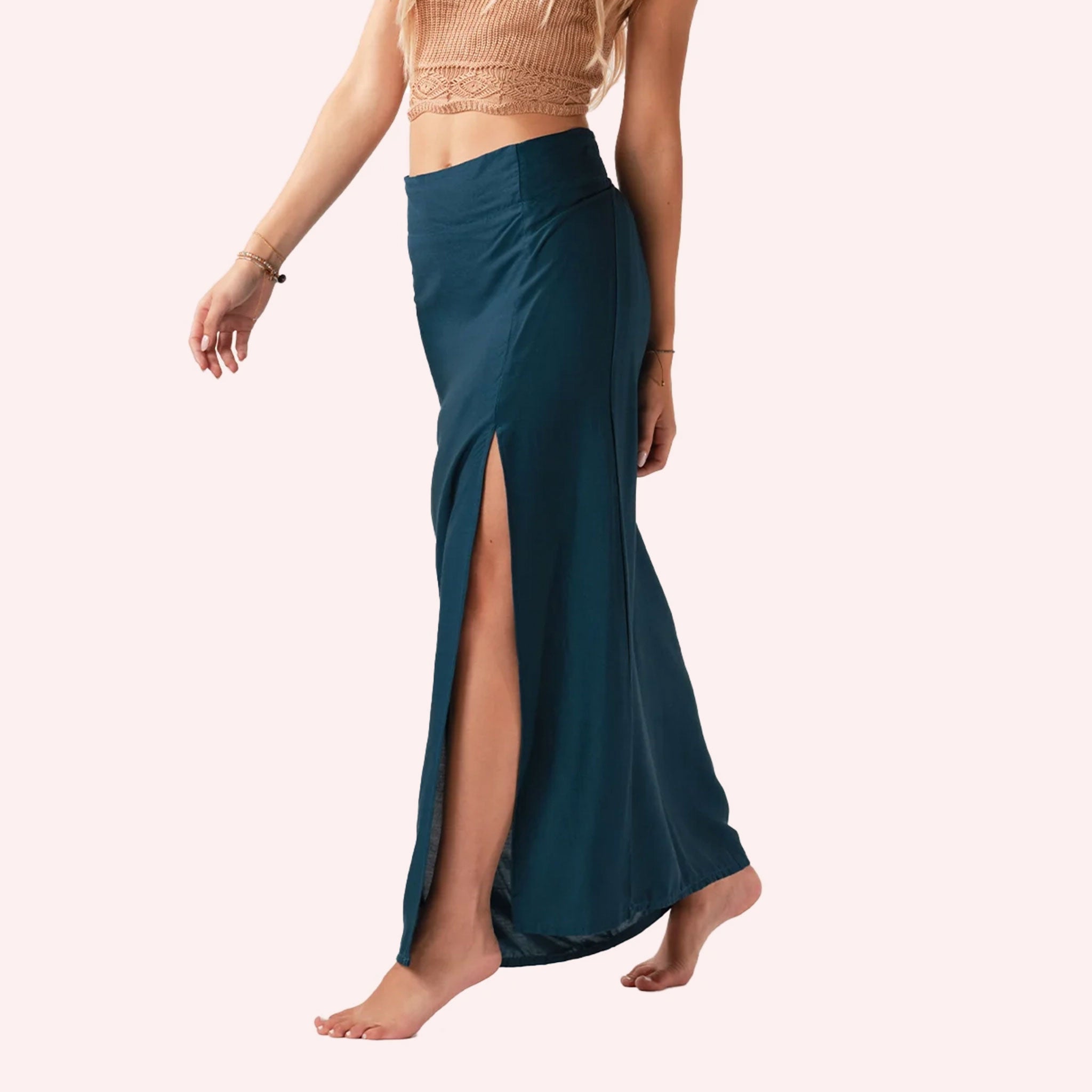 On a neutral background is a teal maxi skirt with a slit on the front side.