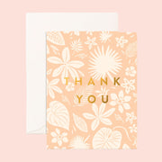 On a pink background is a pink and white tropical floral print card with gold text in the center that reads, "Thank You". 