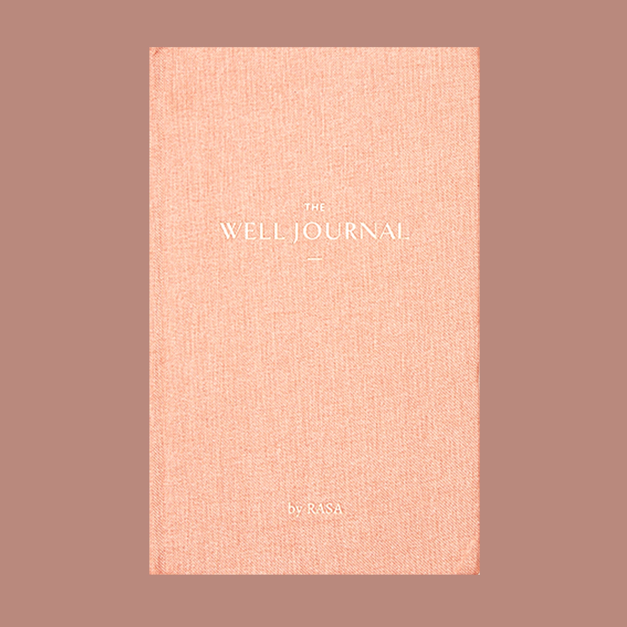 This hardcover journal is titled 'The Well Journal' pressed in gold foil print. The cover itself is a high quality texture covered in warm toned, pink bookcloth. 