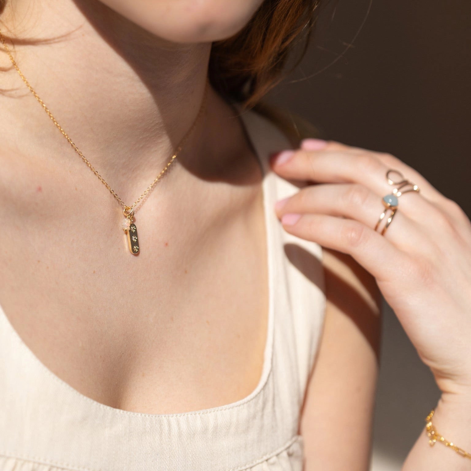 A model wearing a gold necklace with 3 stones on it.