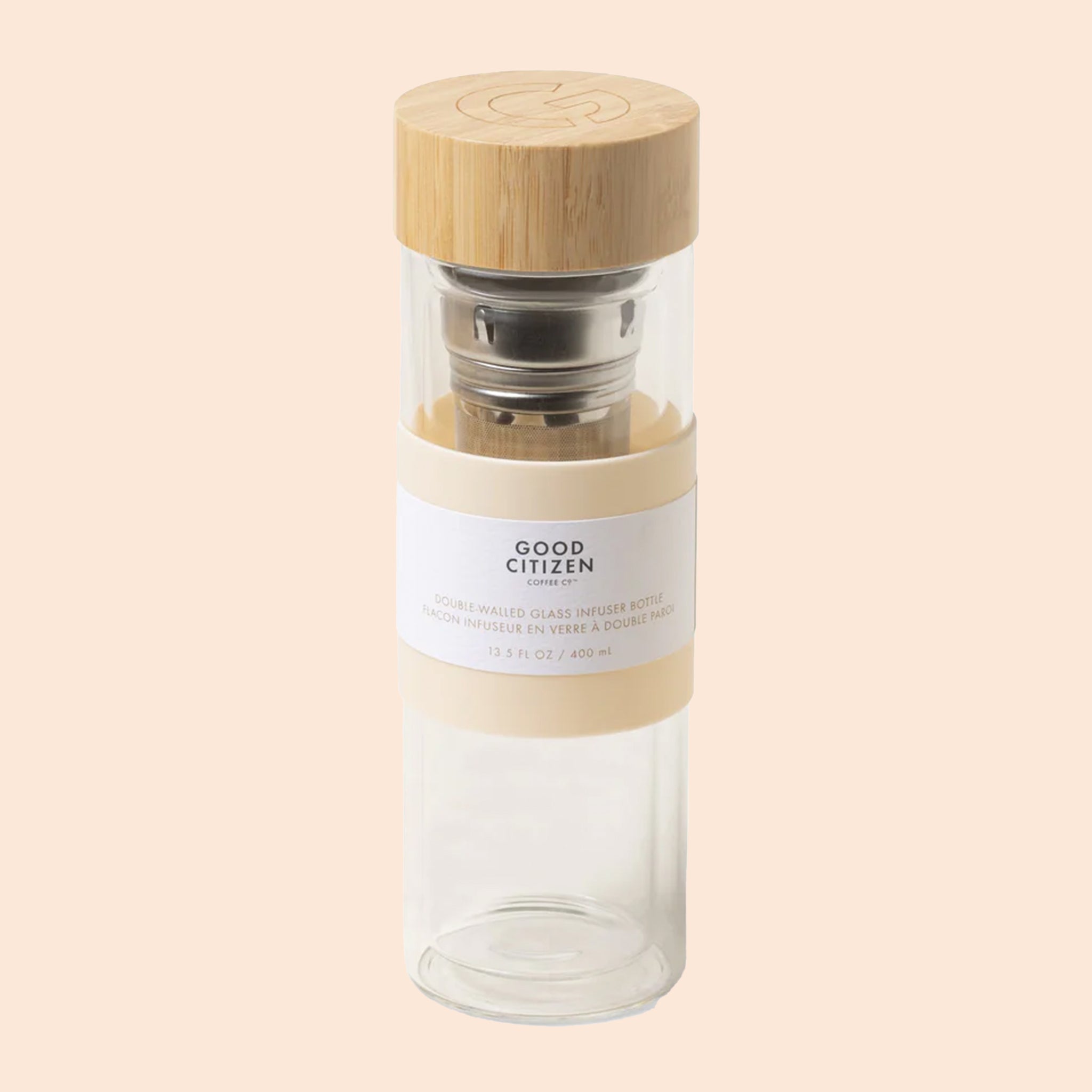 On a cream background is a glass bottle with a bamboo lid and a infuser on the inside. 