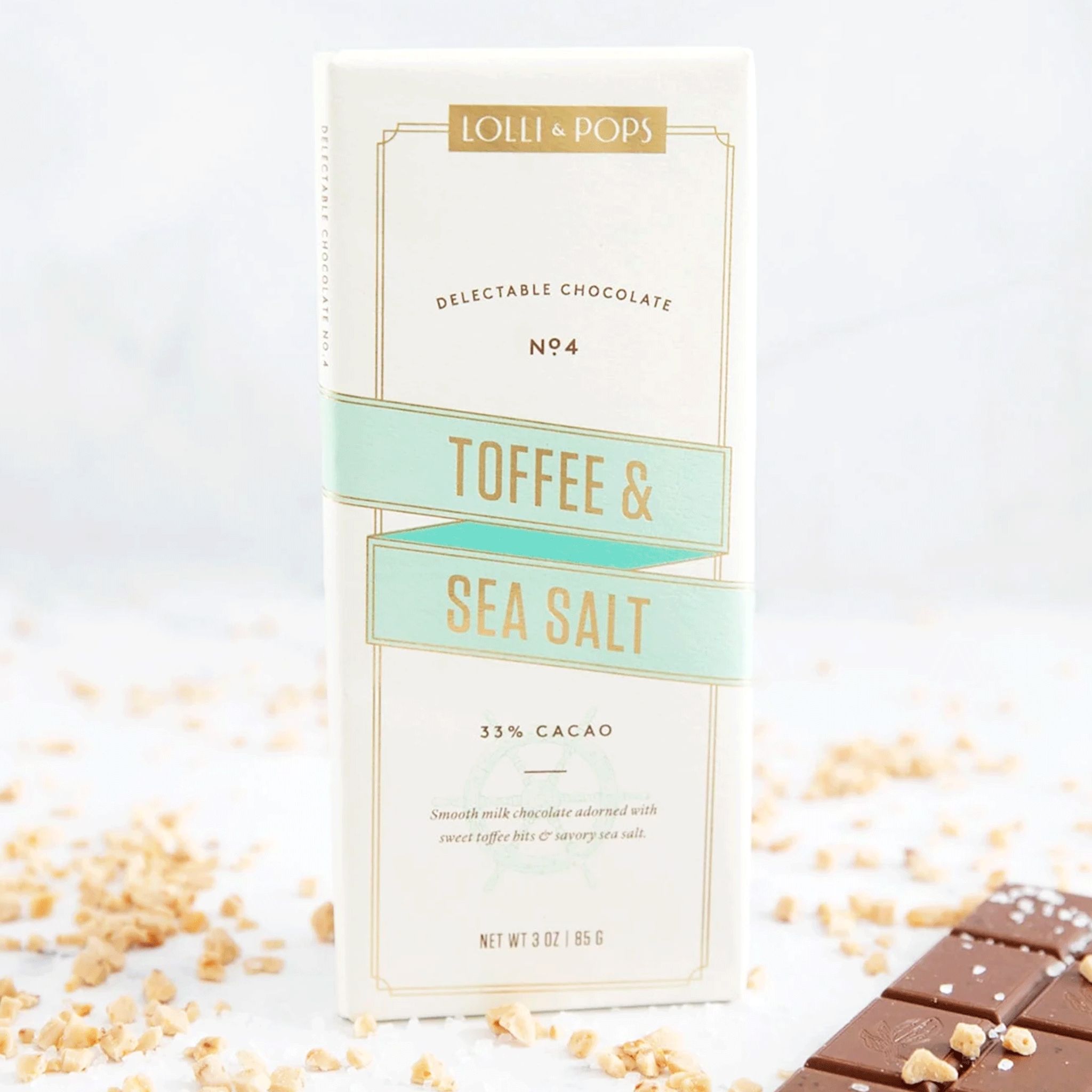 On a white background is a neutral colored package of a chocolate bar with toffee and sea salt. 