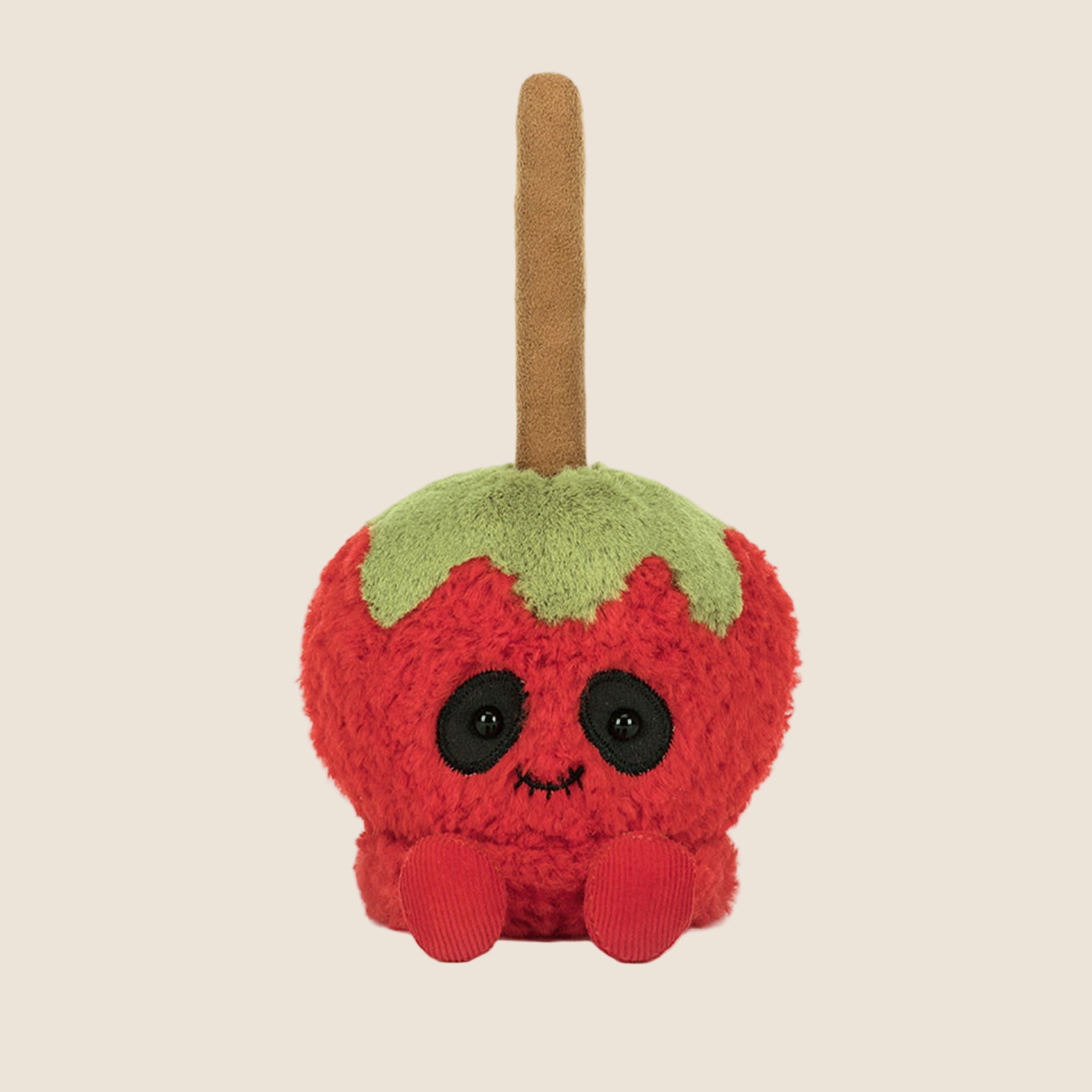 A red and green caramel apple shaped stuffed toy. 