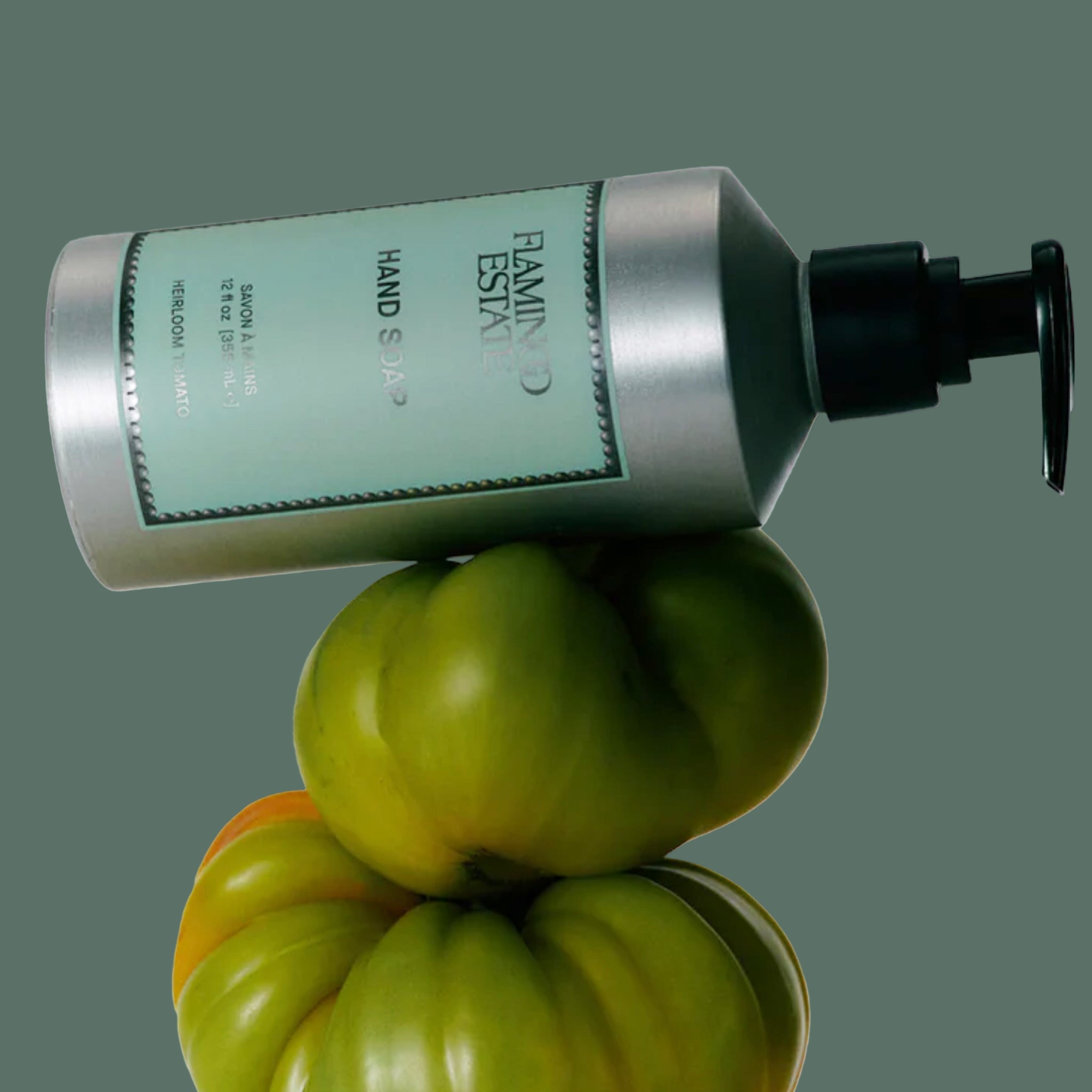 A silver bottle of soap with a light teal label with black text that reads, 'Flamingo Estate Hand Soap". 