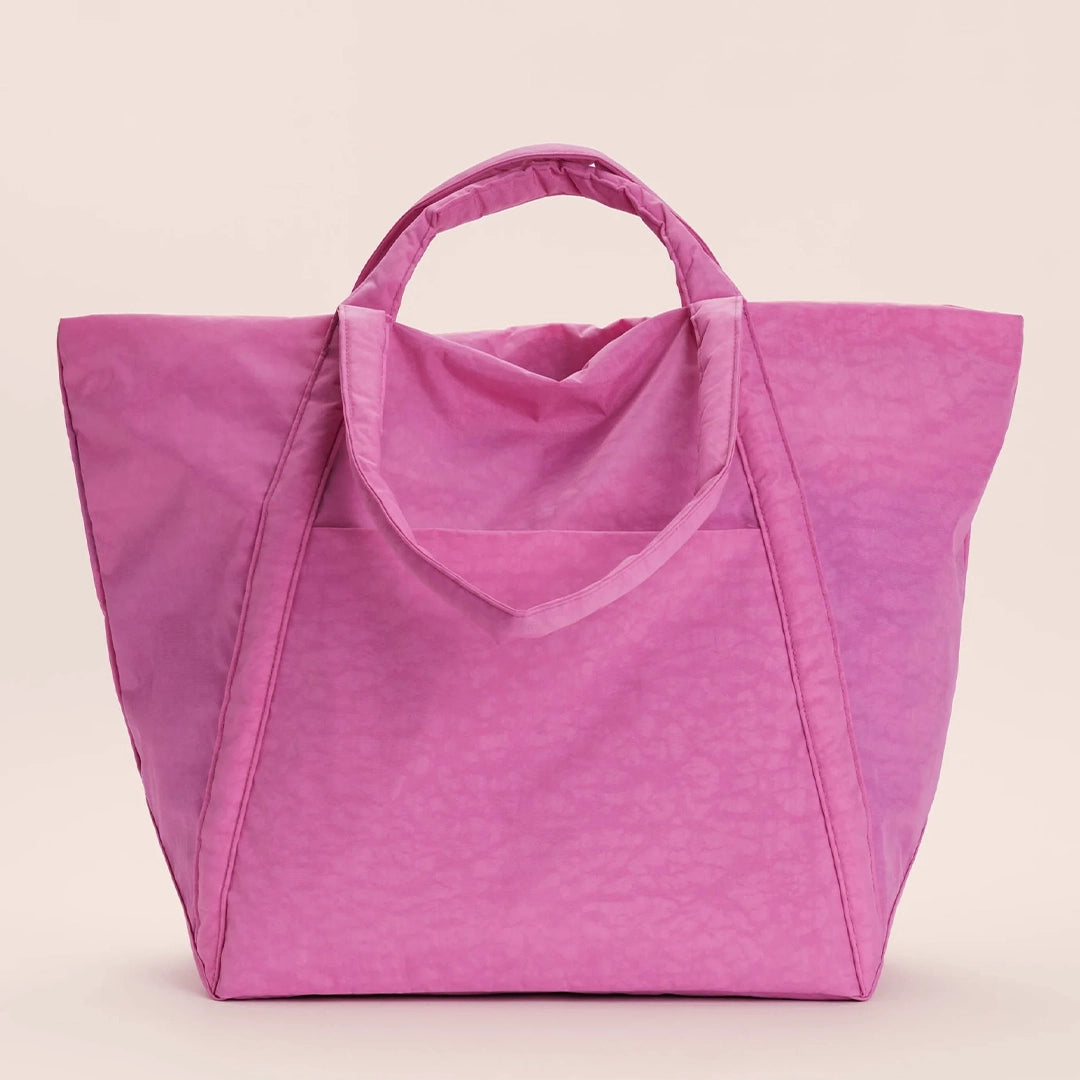 On a cream background is a nylon tote bag in a bright pink shade with two handles and an outside pocket. 