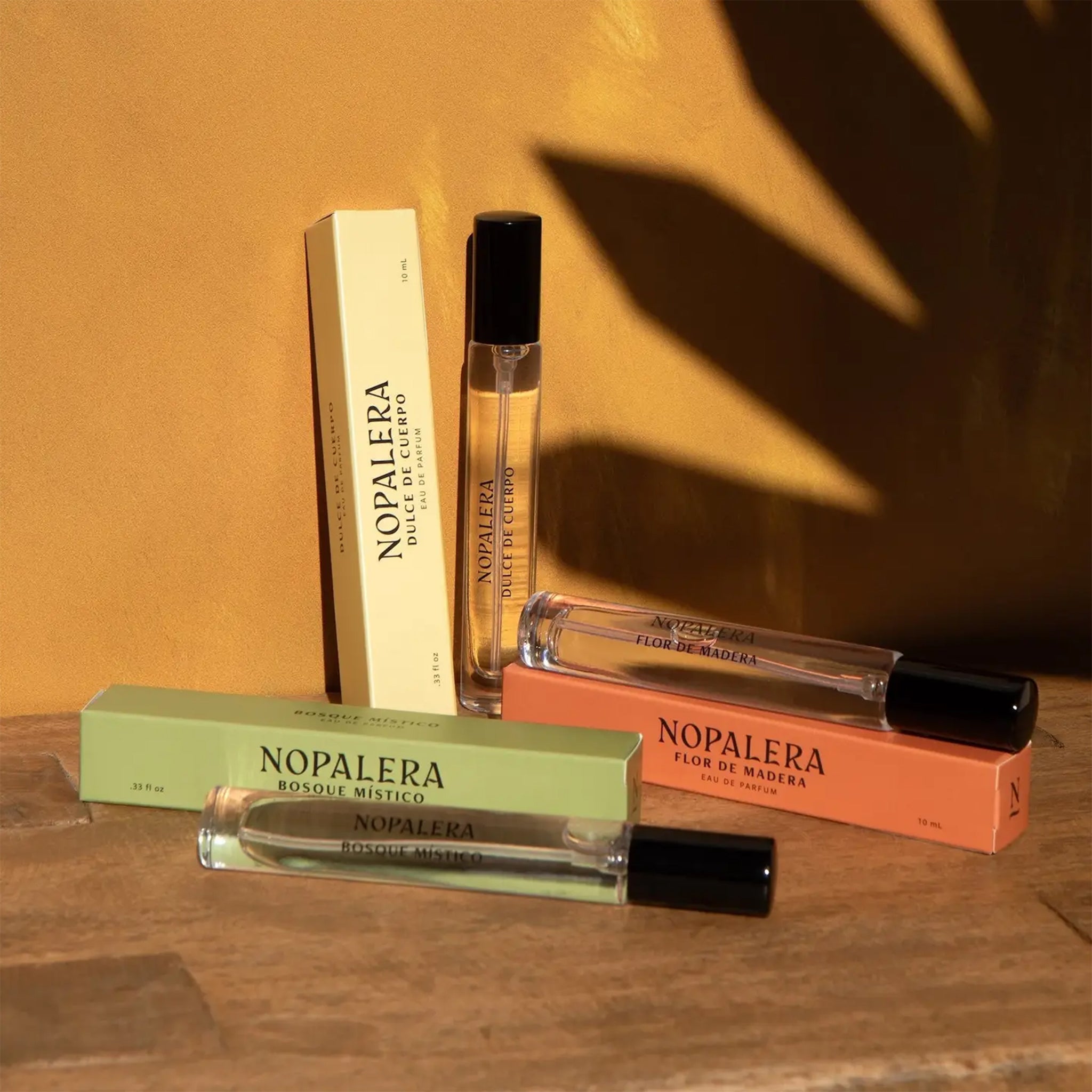 A set of three travel sized fragrances, one with a yellow box, one with an orange and one with a green. Each reads, "Nopalera". 