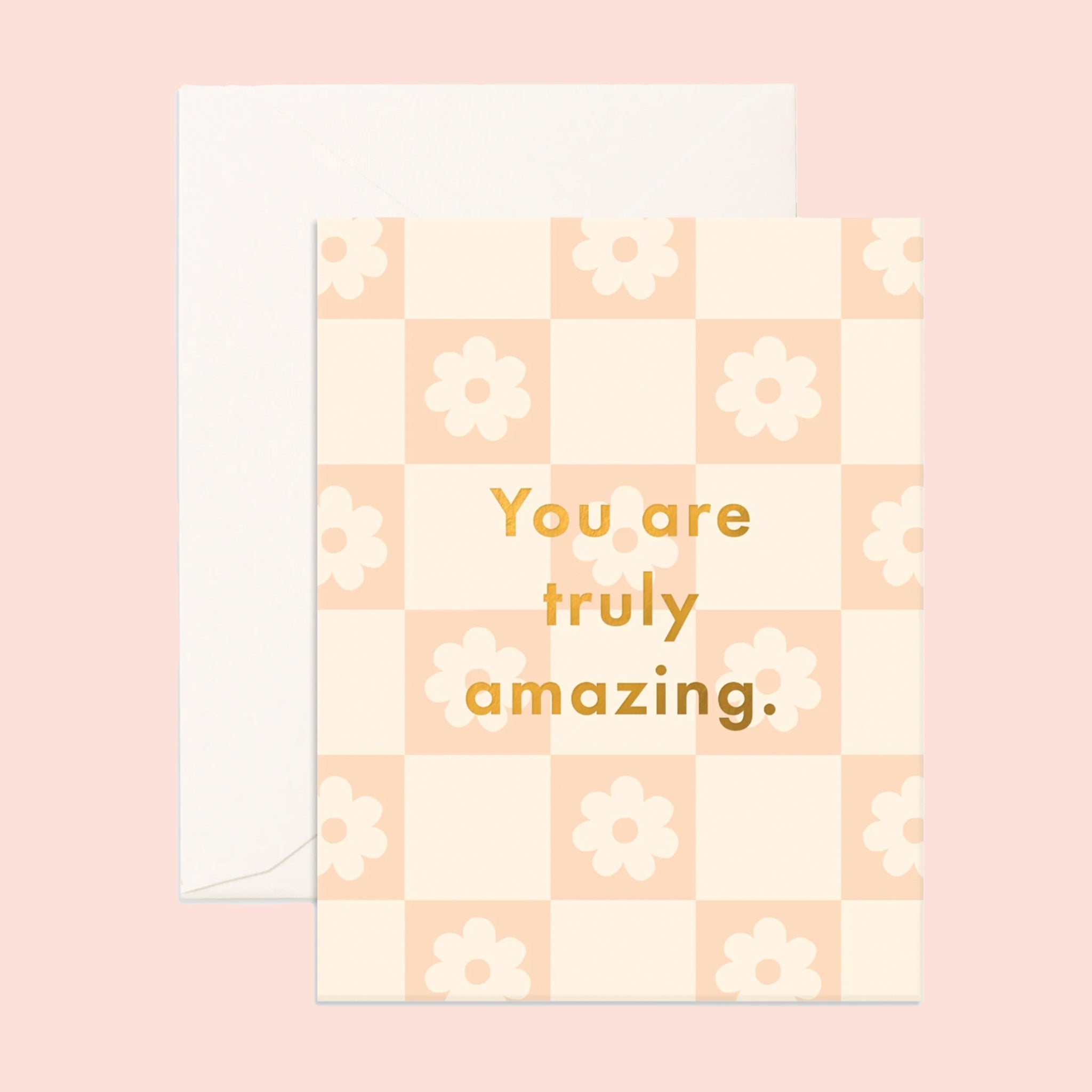 On a pink background is a daisy print checker card with gold text in the center that reads, "You are truly amazing."
