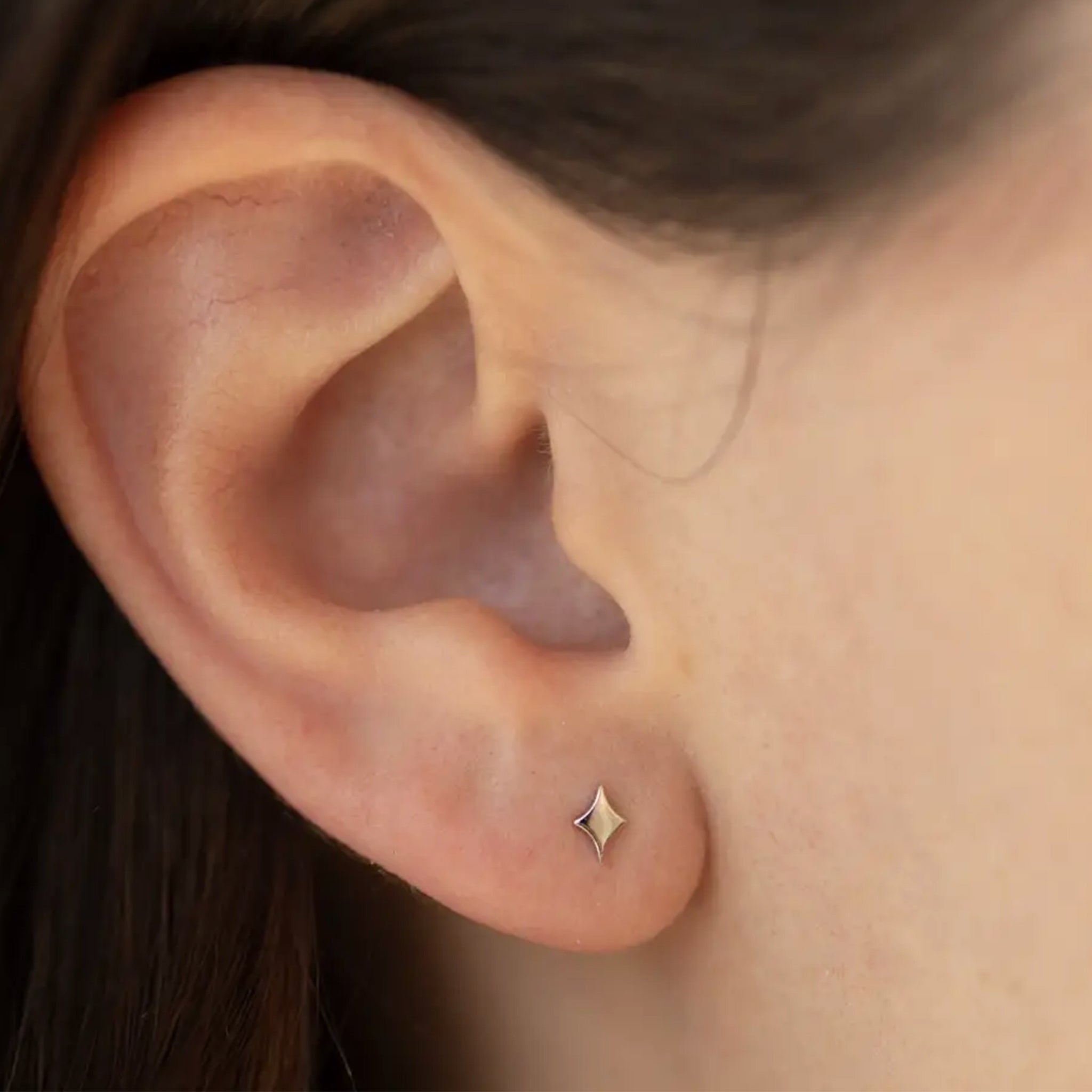 A silver pair of twinkle star shaped stud earrings. 