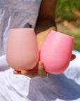 A pair of two pink and peachy silicone stemless wine glasses for on-the-go beverages. 