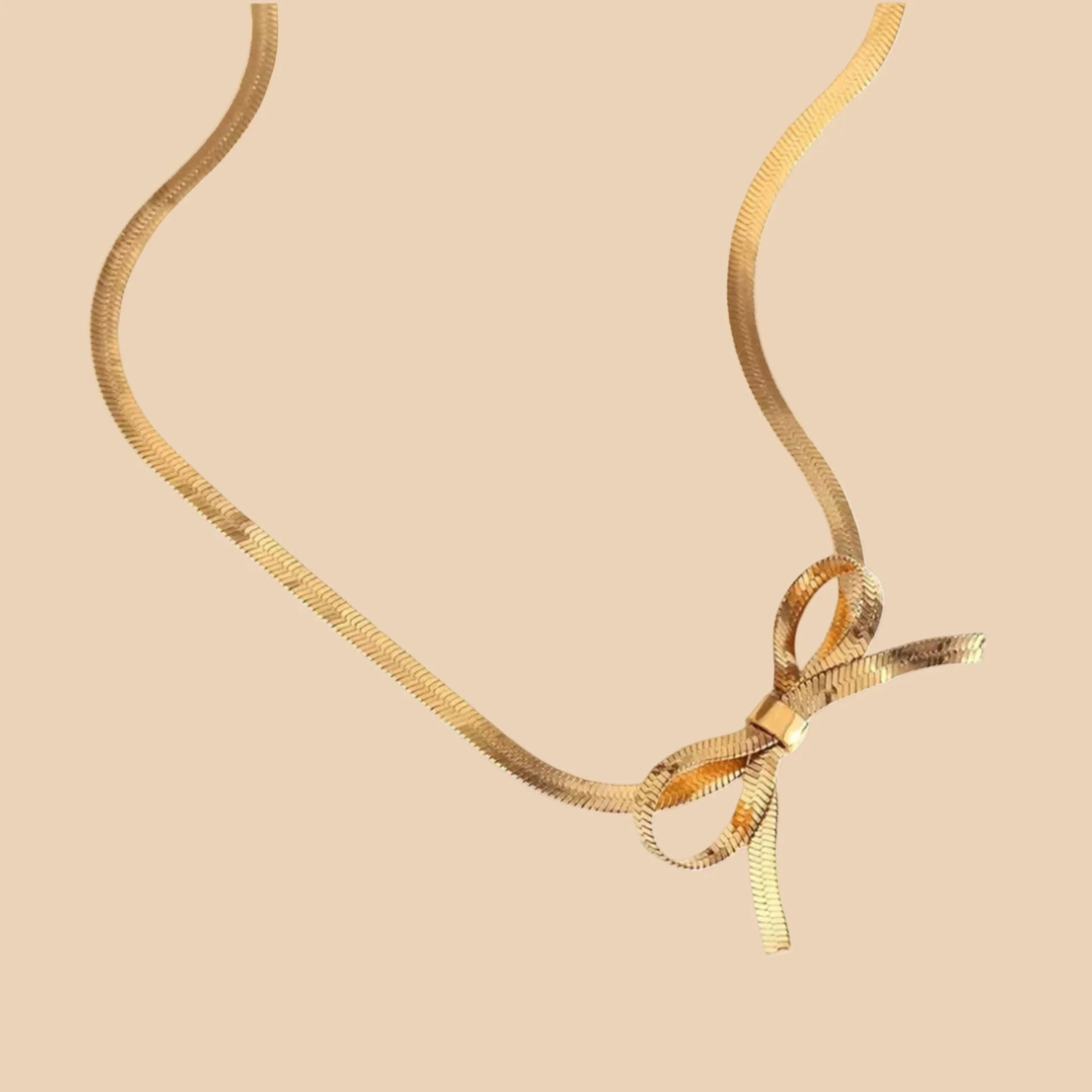 A gold herringbone chain necklace tied in a bow. 