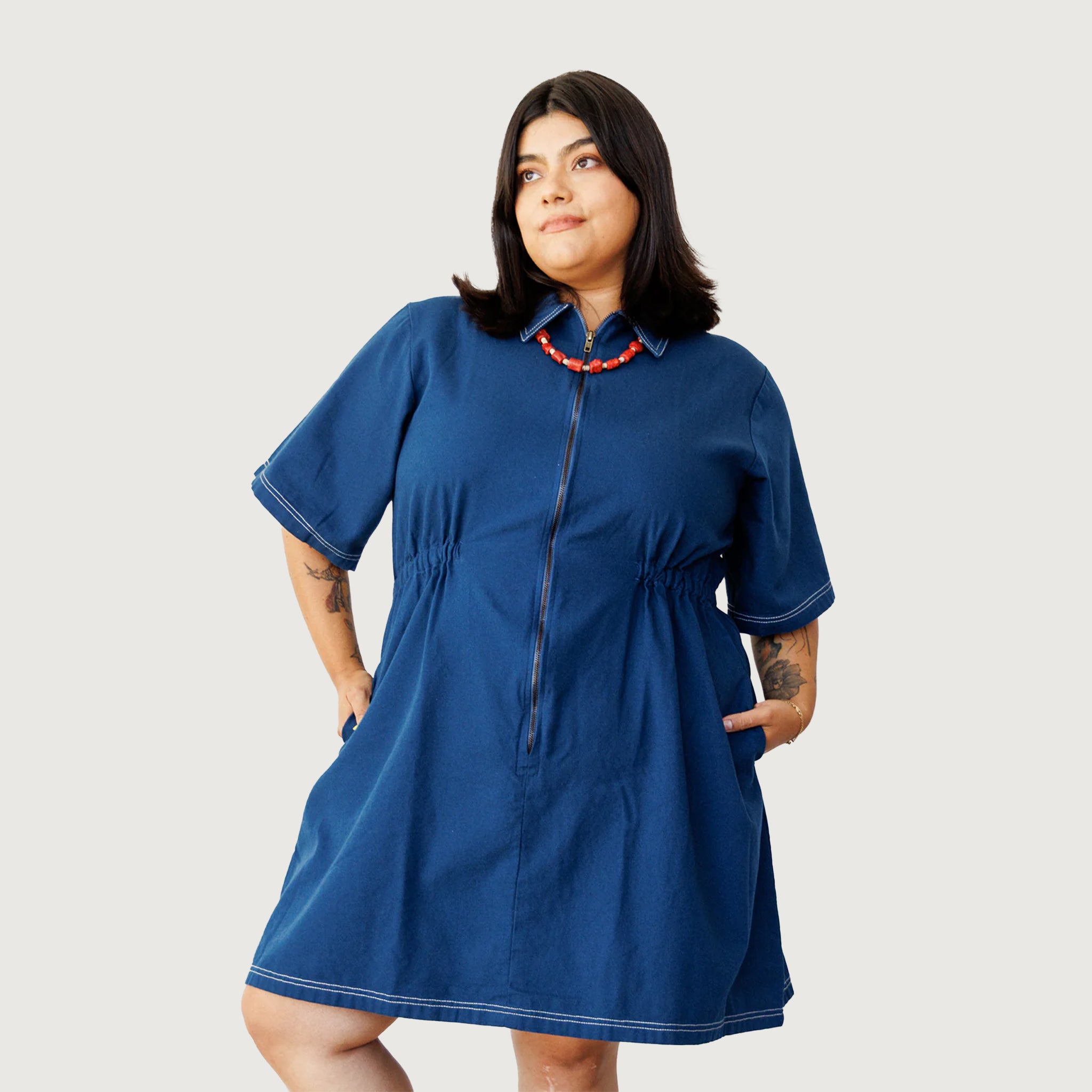 A model wearing a navy blue short sleeve utility dress with a zipper up the front.