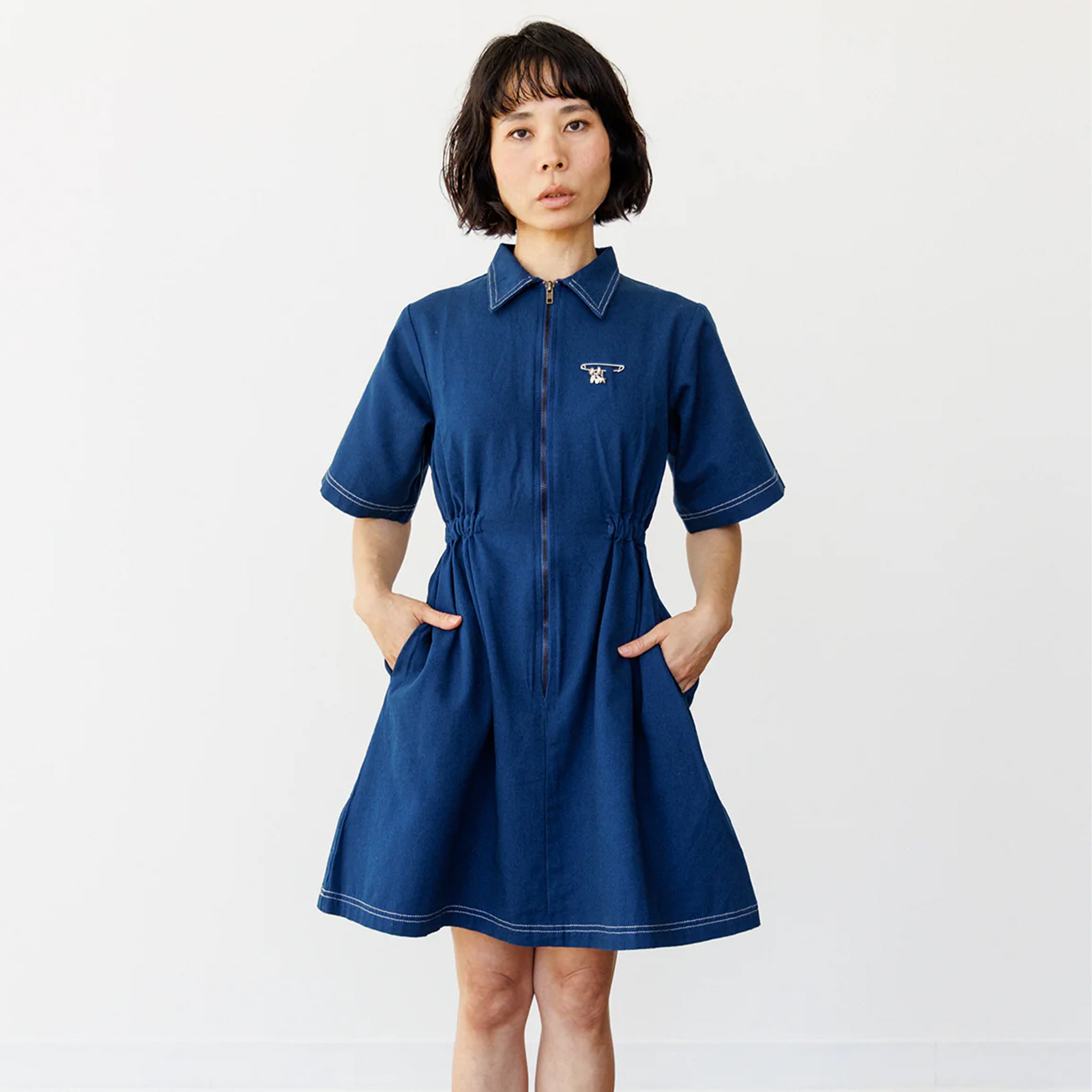 A model wearing a navy blue short sleeve utility dress with a zipper up the front.