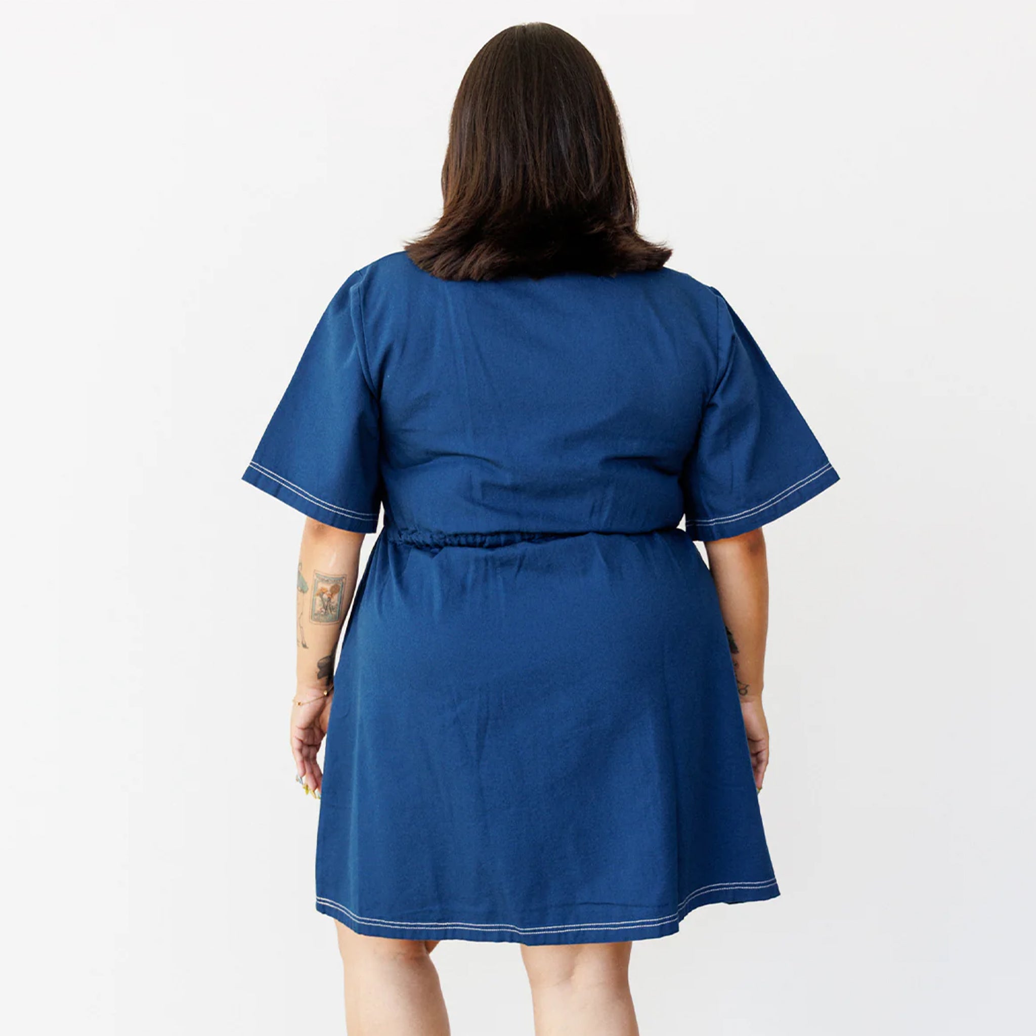 A model wearing a navy blue short sleeve utility dress with a zipper up the front.