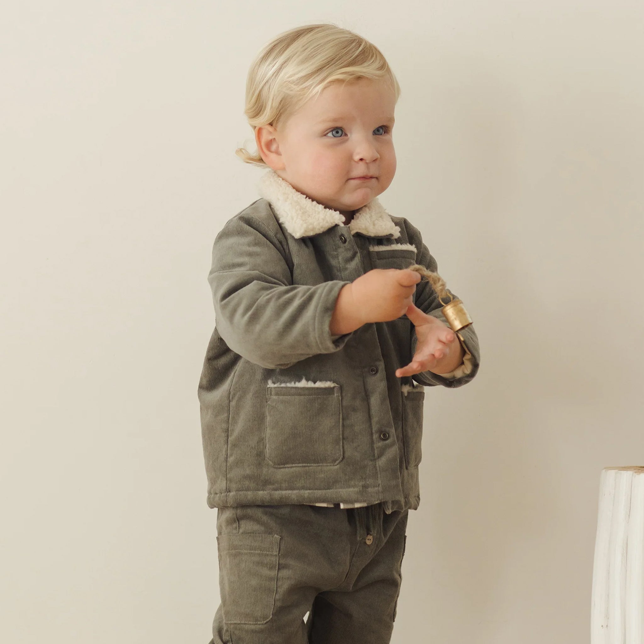 A green utility jacket with a cream colored boucle collar. 