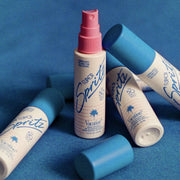 On a blue background is a spray bottle of facial mist with a white bottle, pink spray and blue cap. The text on the bottle reads, "Super Spritz" in blue letters.