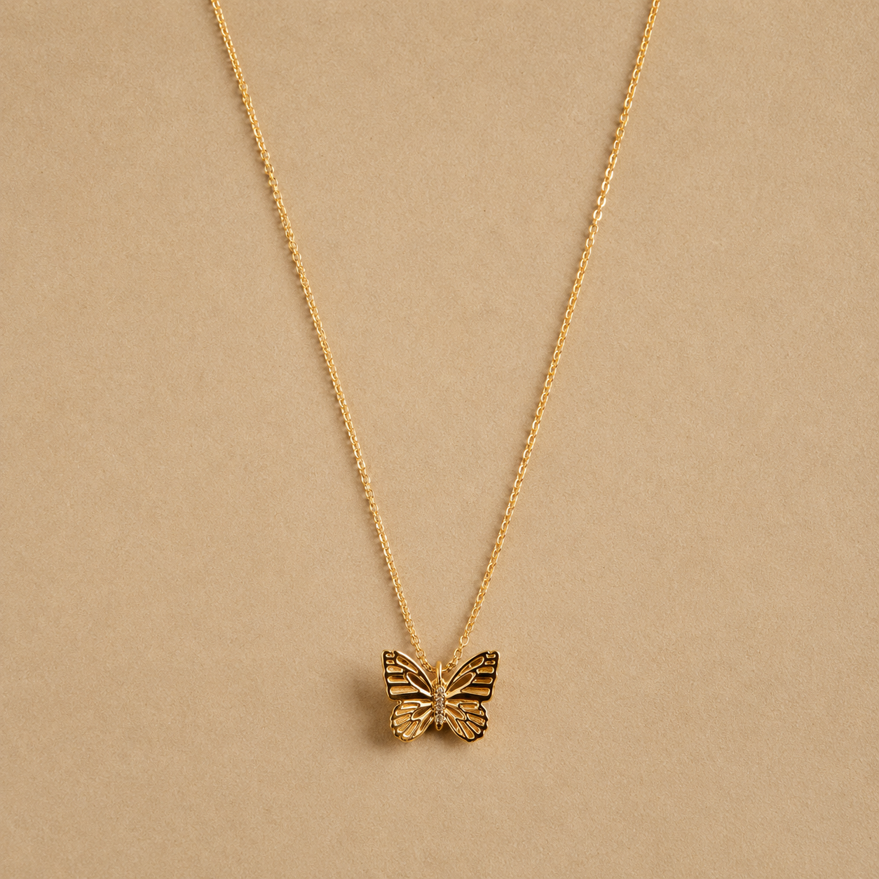 a gold chain necklace with a butterfly pendant in the center. 
