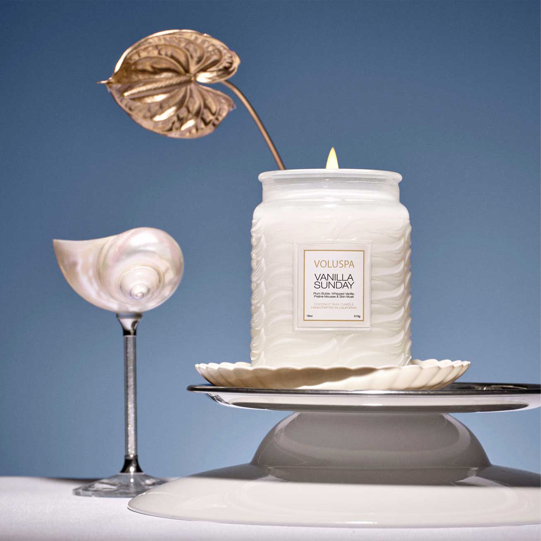 A white large jar glass candle with a rectangle label that reads, "Voluspa Vanilla Sunday". 