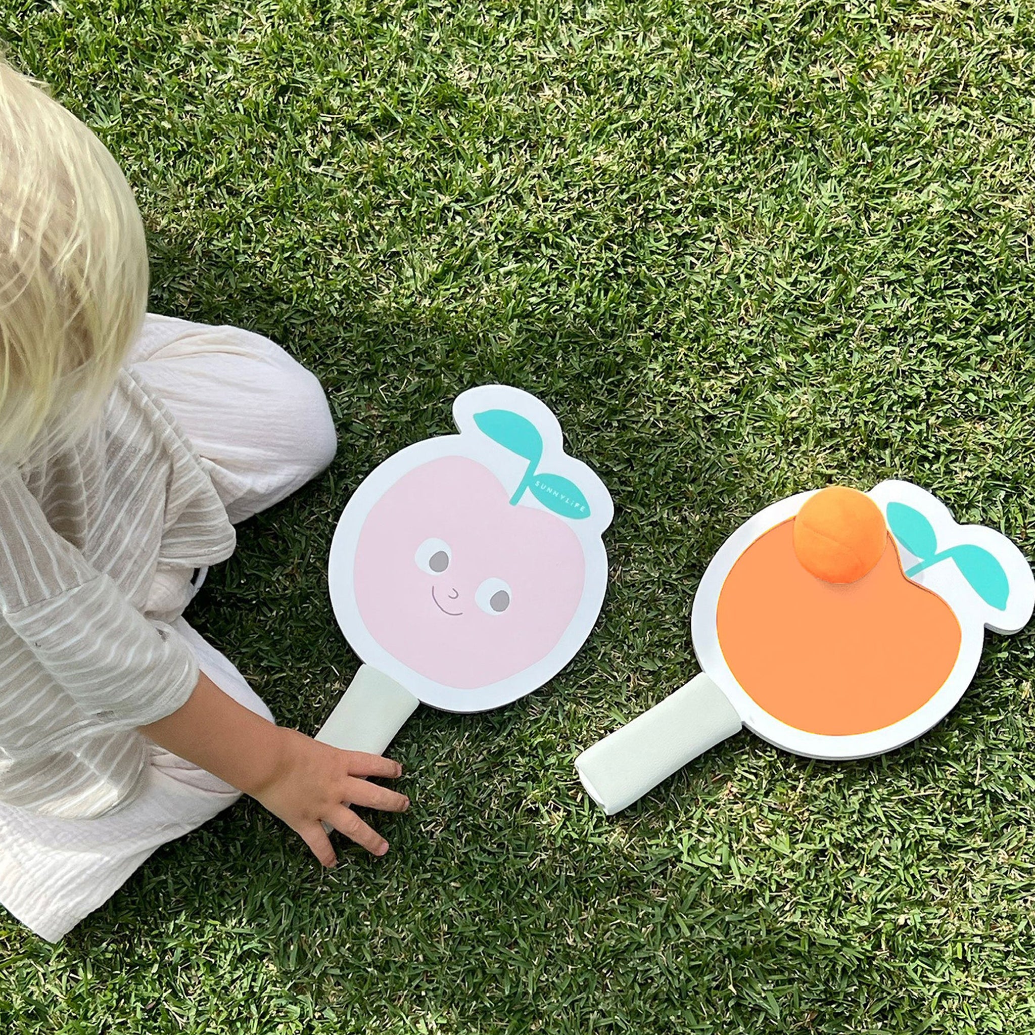 Two peach shaped paddle beach velcro bat toys with a orange ball. 