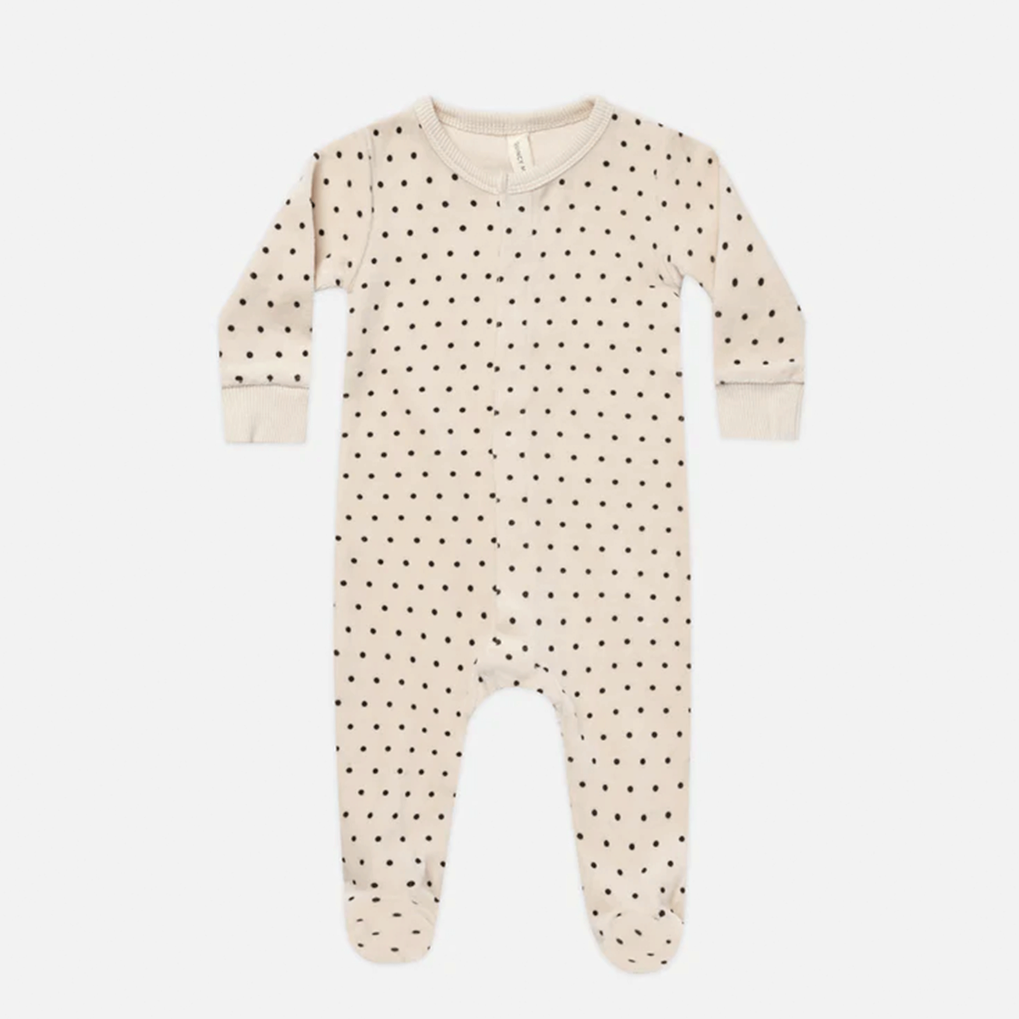 On a white background is ivory onesie pajamas with black polka dots. 