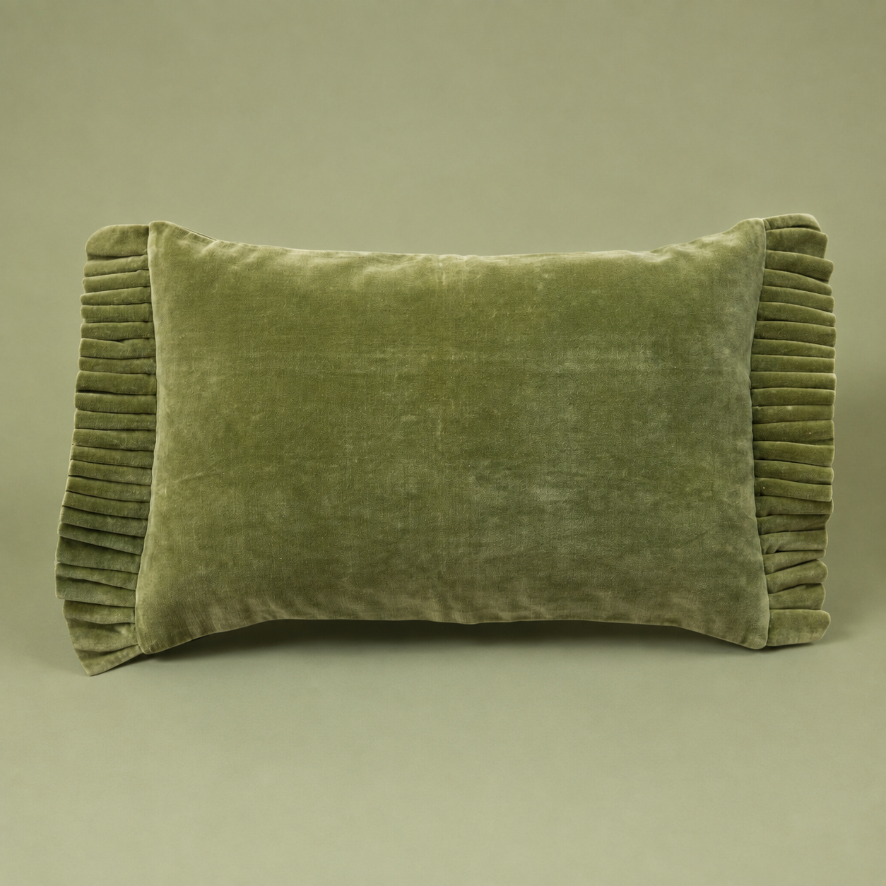 An olive green velvet lumbar pillow with pleated edges, shown against a solid taupe background.