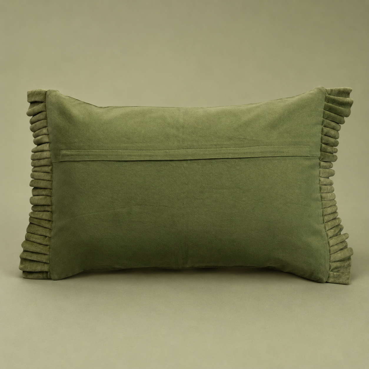 An olive green velvet lumbar pillow with pleated edges, shown against a solid taupe background.