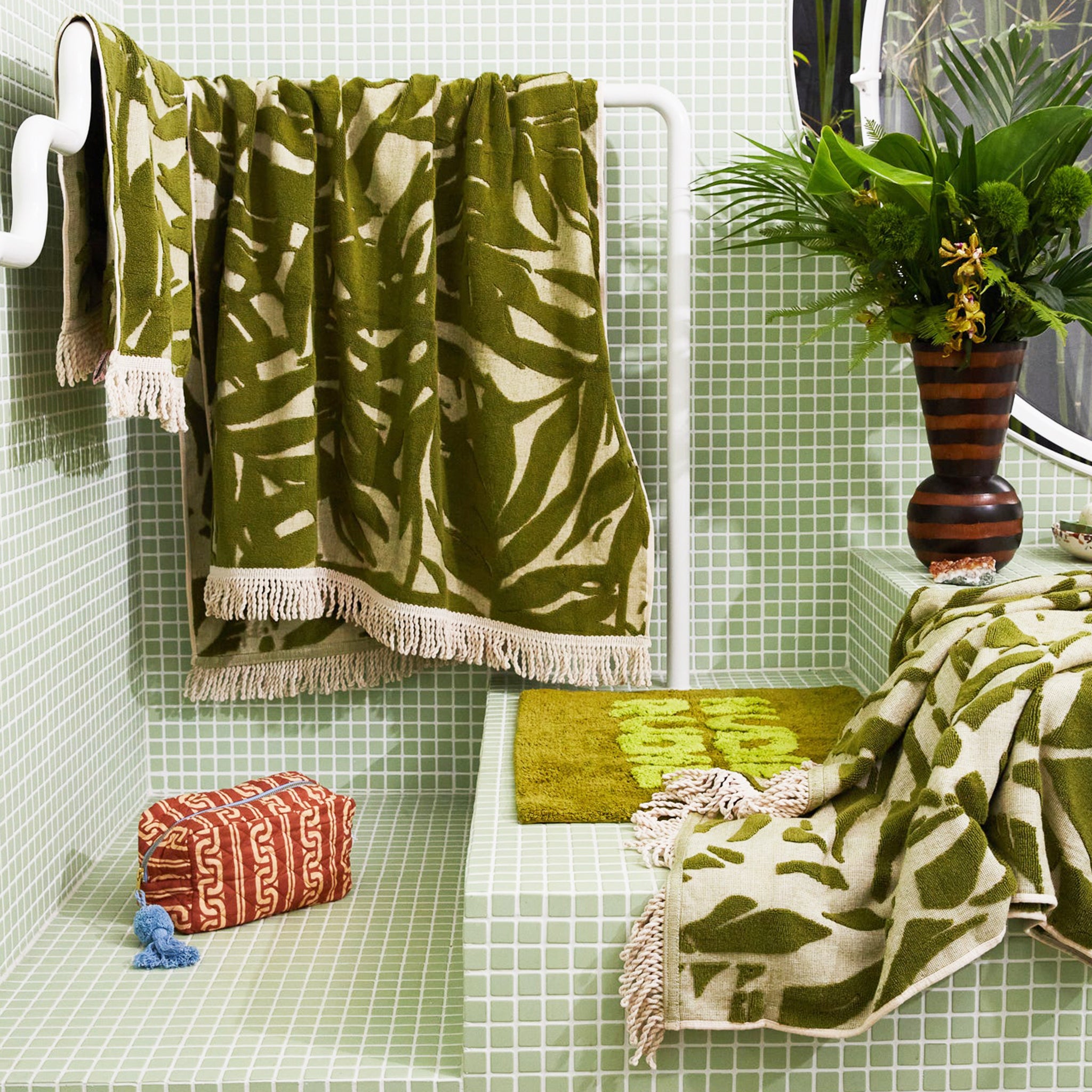 A green and ivory bamboo printed bath towel with tassel ends on both sides.
