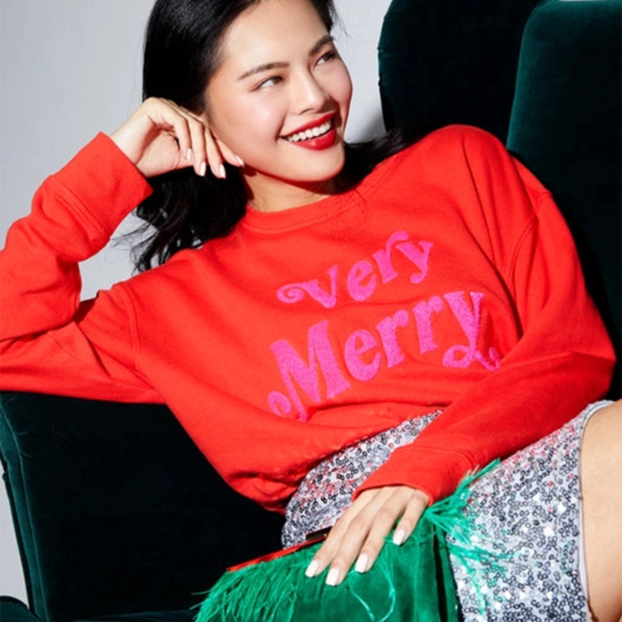 A model wearing a red sweatshirt with hot pink text across the front that reads, &quot;Very Merry&quot;.