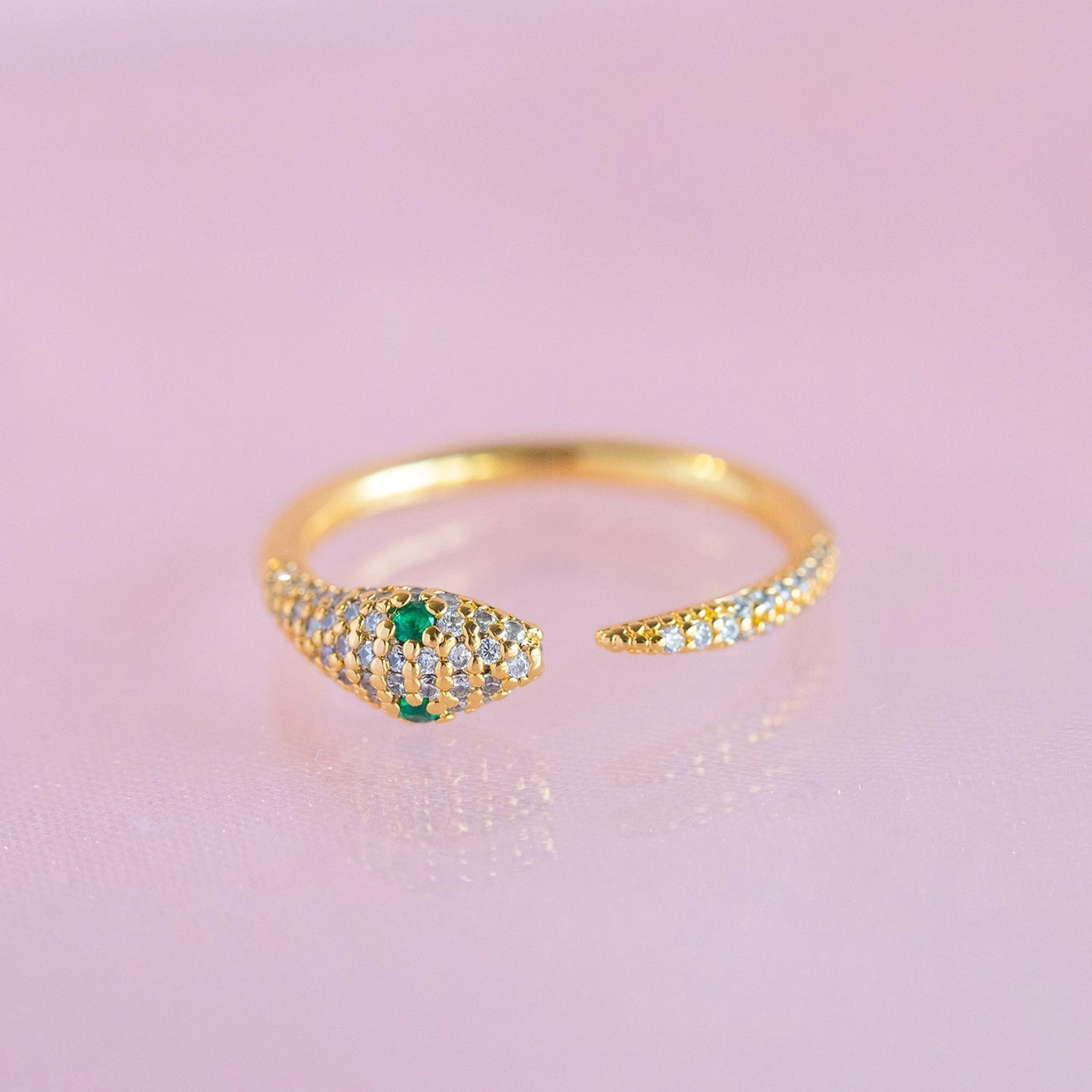 A gold snake design ring with green cz stones as eyes. 