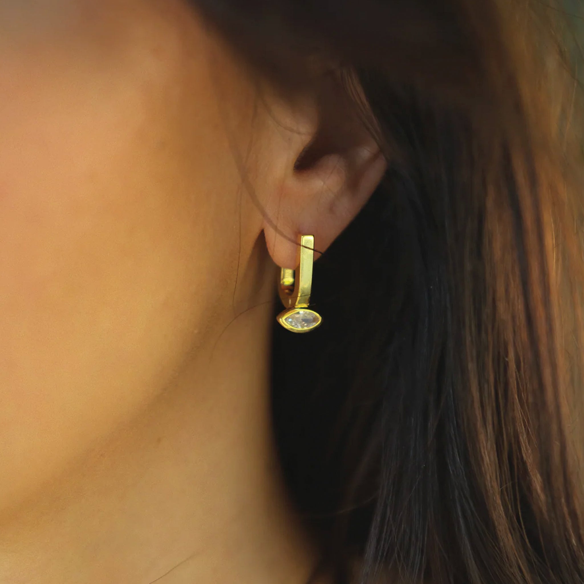 A pair of gold hoops with a marquise shaped cz stone in the center off the bottom. 