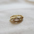 A gold chunky ring with a marquise shaped stone in the center situated in a horizontal setting. 