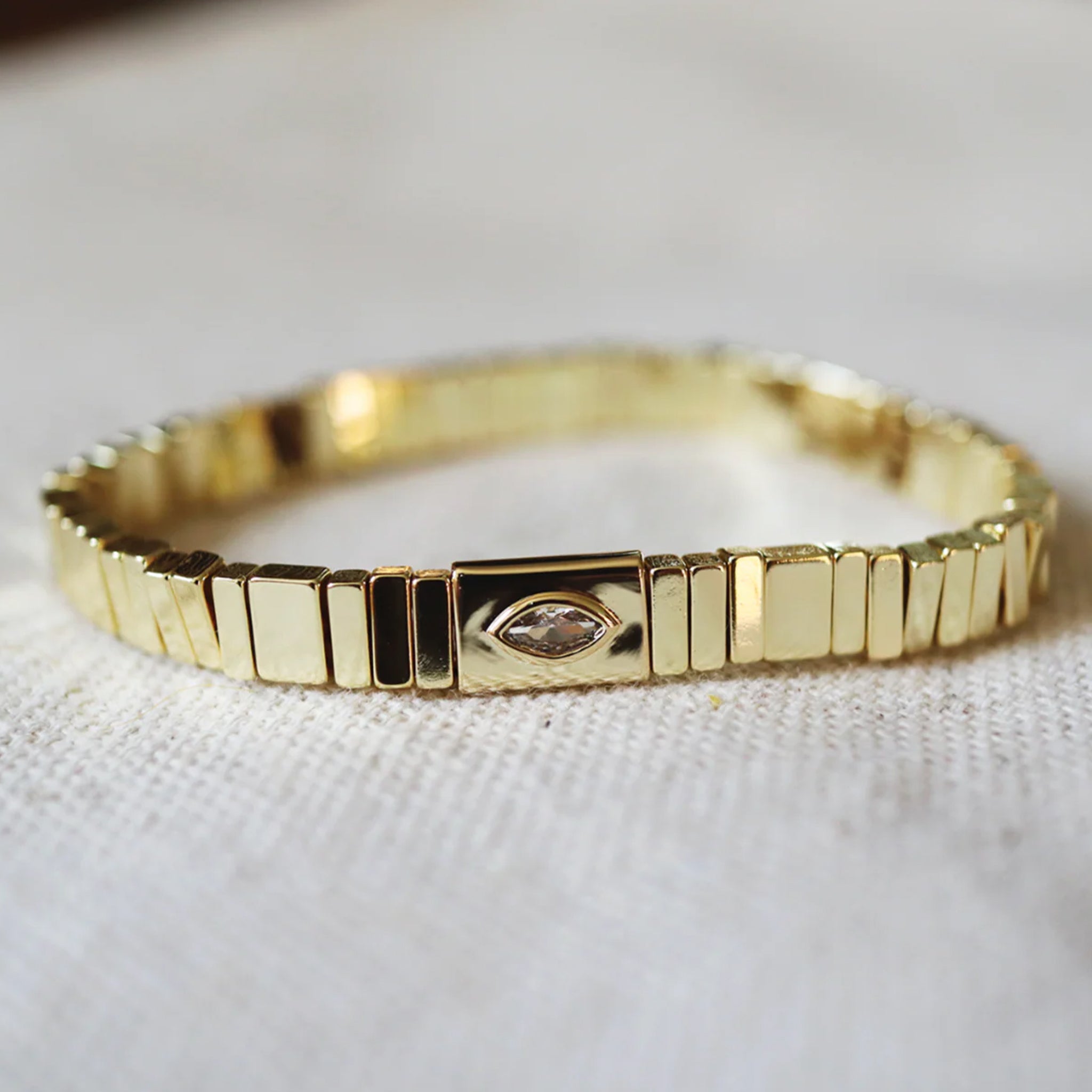 A gold beaded stretch bracelet with a marquise shaped cz in the center. 