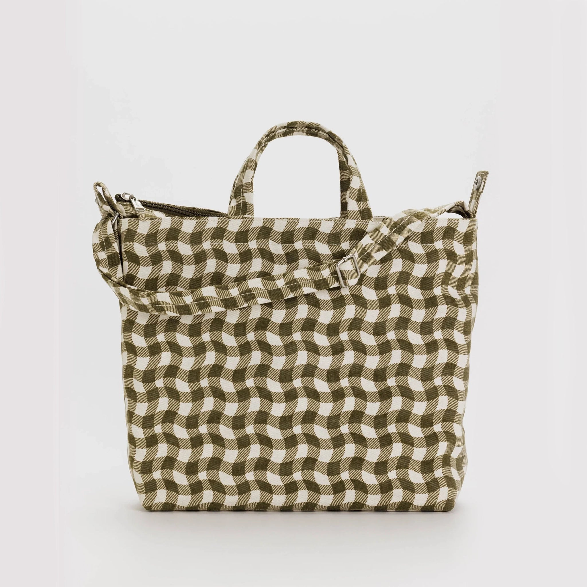 On a white background is a canvas tote bag in a brown and ivory wavy gingham print with a handle and an adjustable strap. 