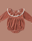 A cranberry colored velvet romper with a white lace ruffle neckline and sleeve. 