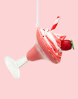 A pink and clear cocktail shaped ornament with a whipped topping and a red and white striped straw with a ribbon loop for hanging. 