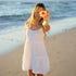 Woman in a white dress holding a flower on a beach