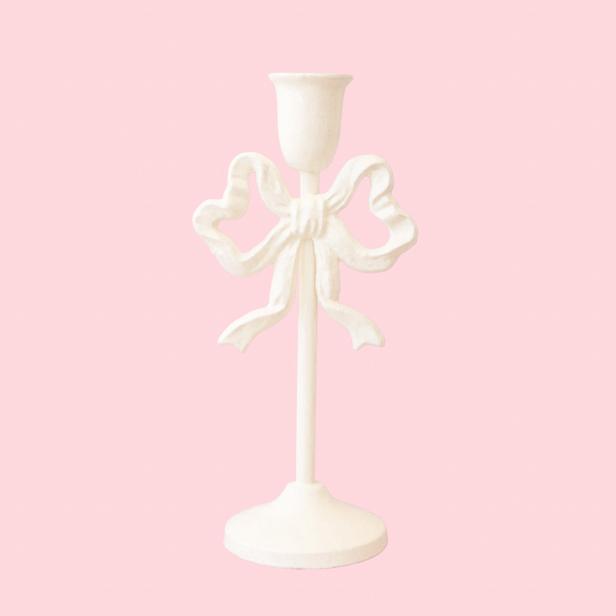 A white taper candle holder with a bow shaped design. 