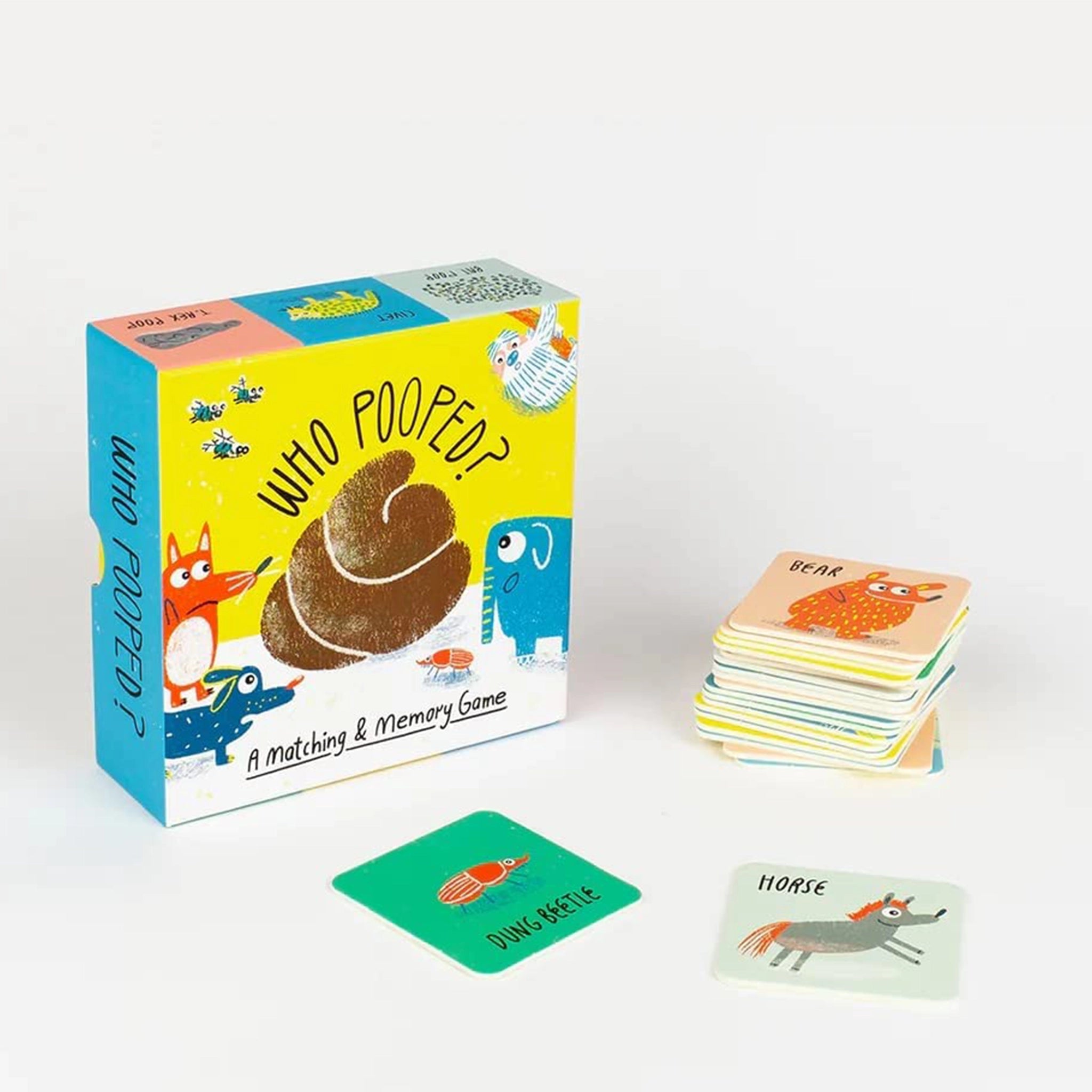 On a white background is a children&#39;s game with a colorful box featuring artwork of a pile of poop and various animal illustrations around it and cards staged outside of the box with animals and their names printed on the front of the card. 