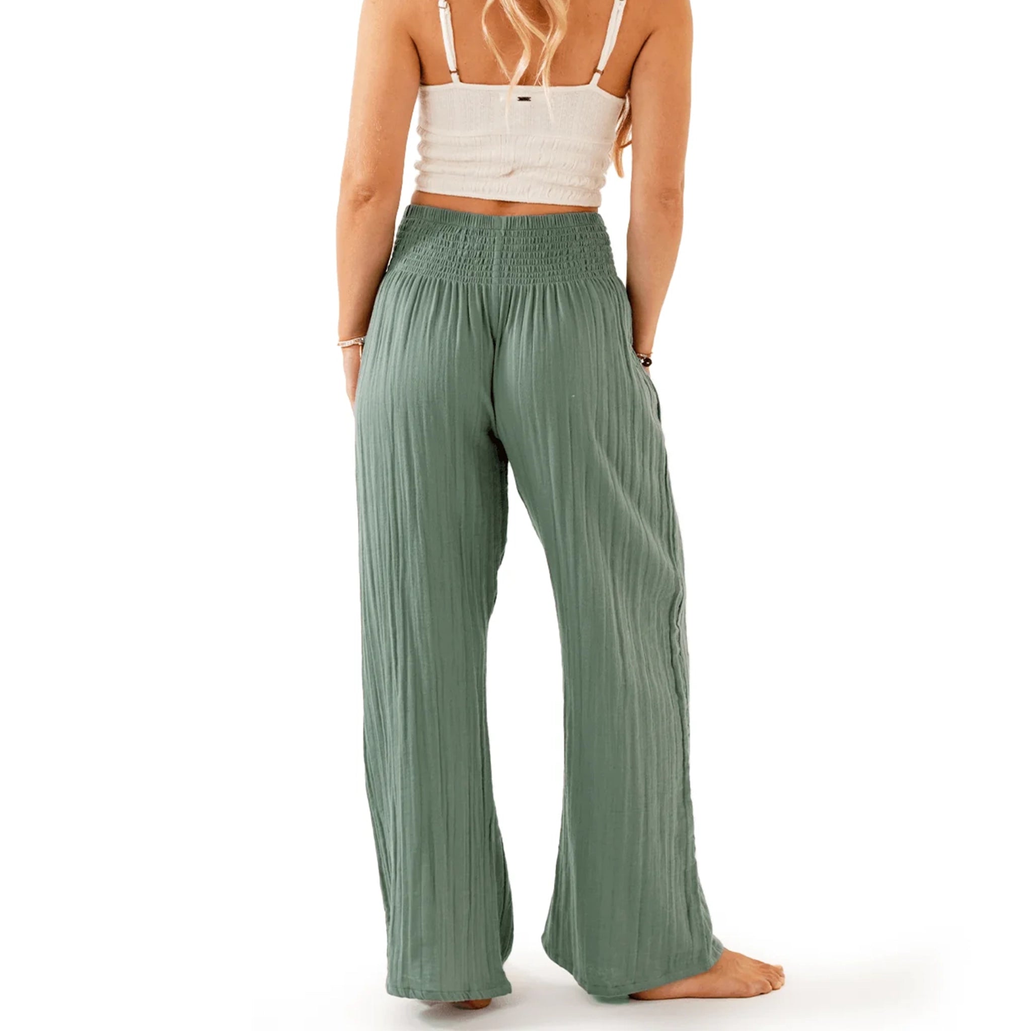 A model wearing a pair of wide leg, sage green pants with a stretchy elastic waistband. 