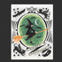 A white card with an illustration of a witch on a broomstick in front of a green background and spooky designs around the edge as well as text that reads, 'Happy Halloween". 