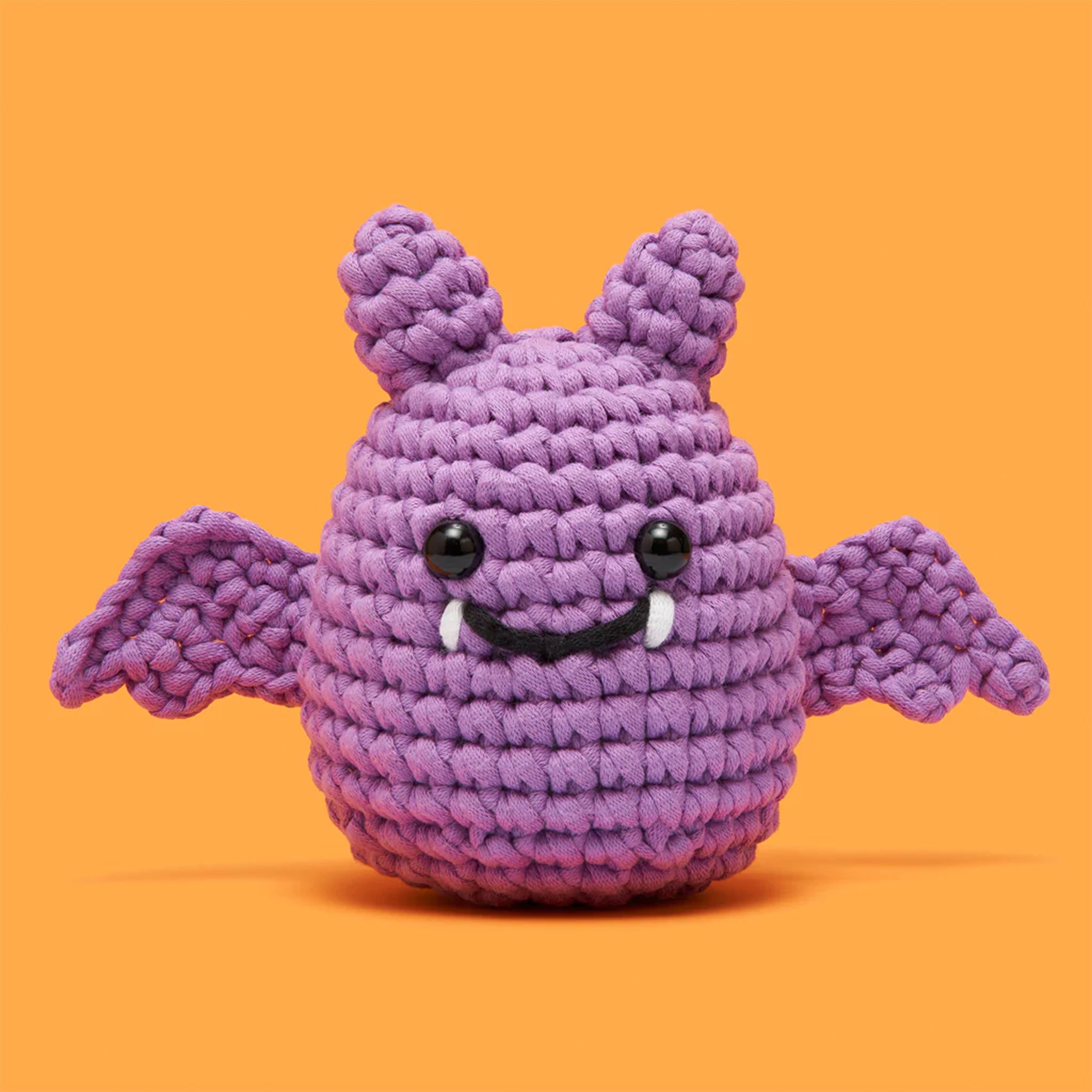A crochet kit that creates a purple bat with a smiling face. 