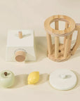 A wooden toy blender with two wooden fruit shaped toys. 