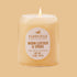 On an orange background is a neutral glass jar candle with an oval label that reads, "Paddywax Worn Leather & Smoke". 