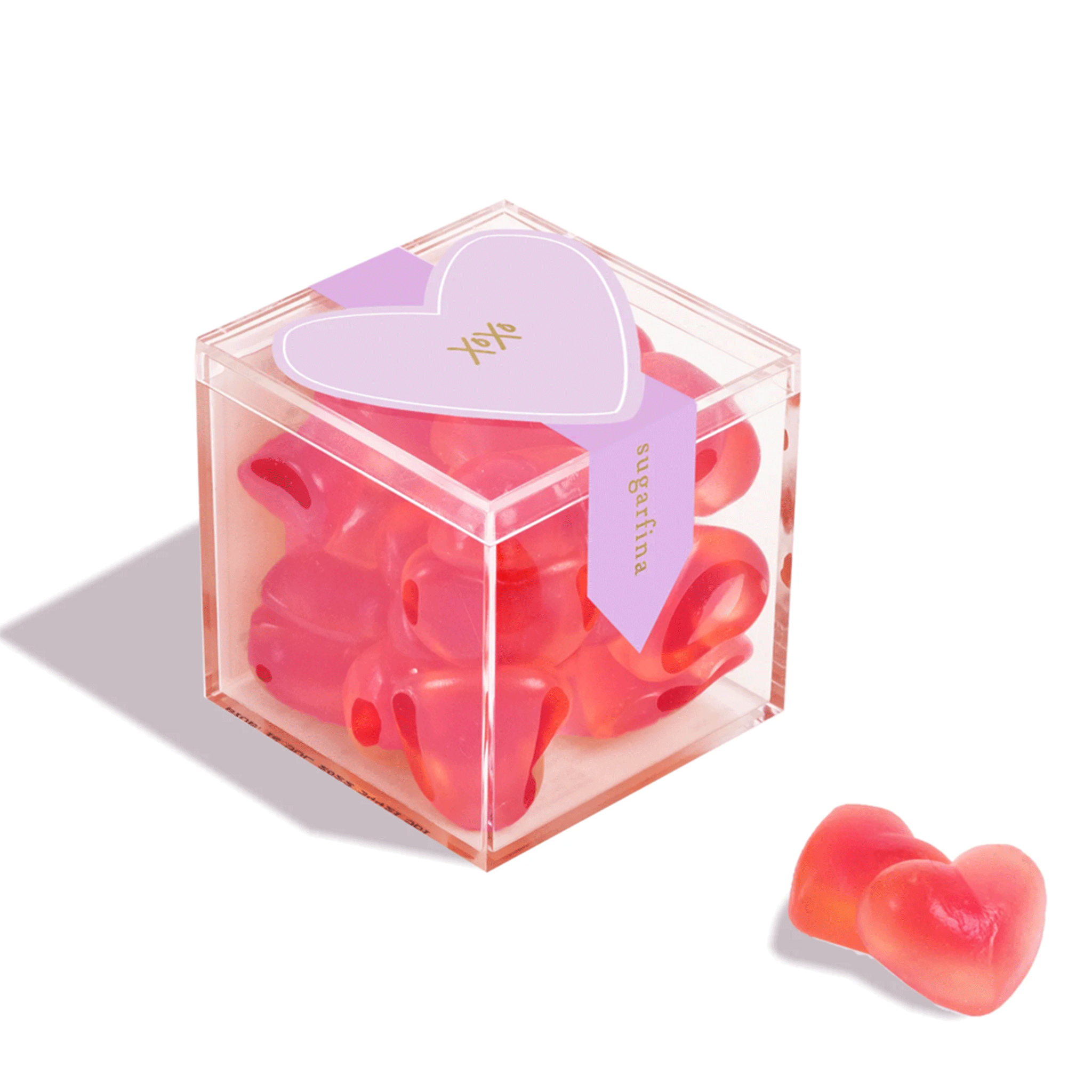 On a white background is an acrylic clear box of red heart shaped gummy candies. 