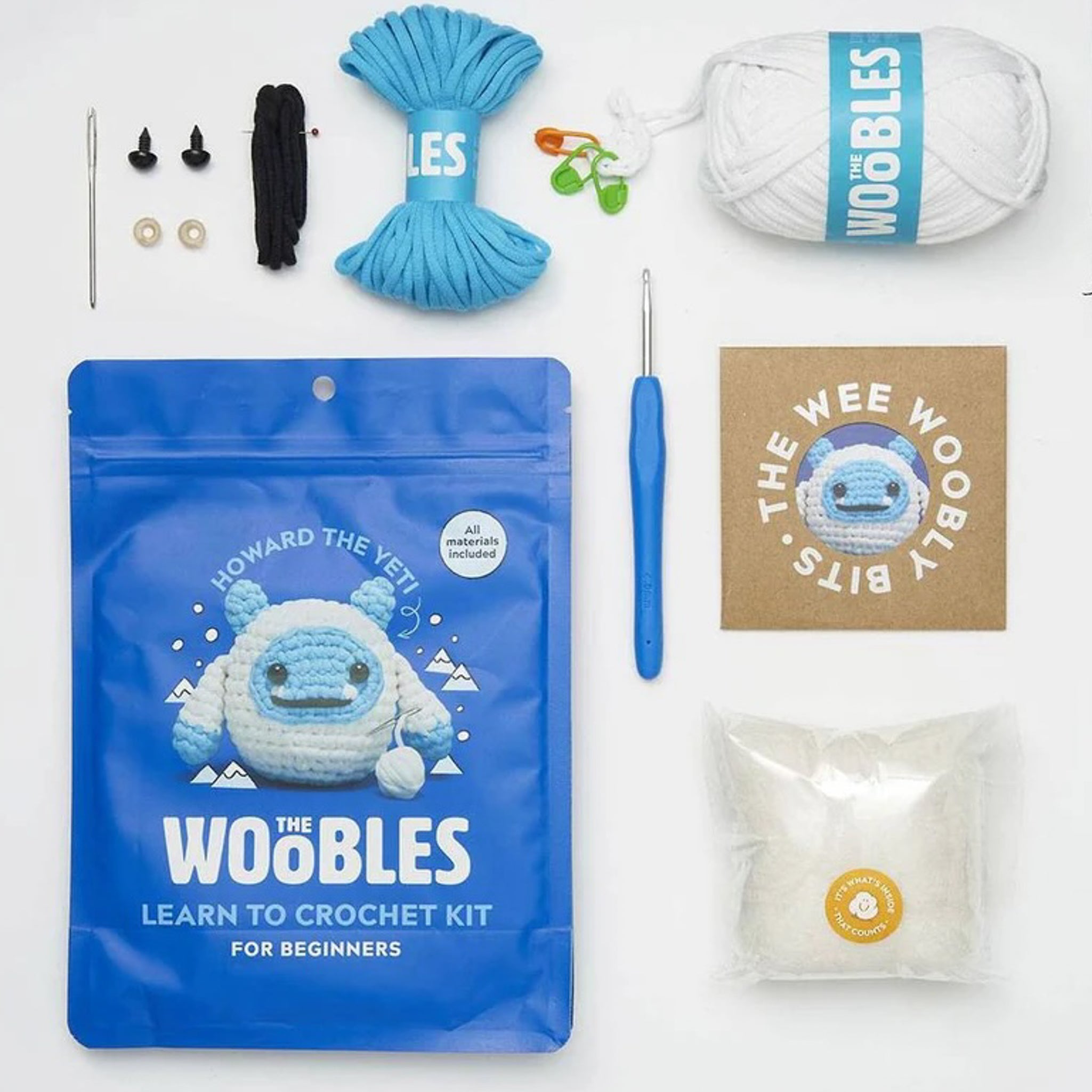 flat lay image of a woobles crochet package that reads "learn to crochet kit".  there is yarn, a crochet needle and other items to create a yeti from yarn.