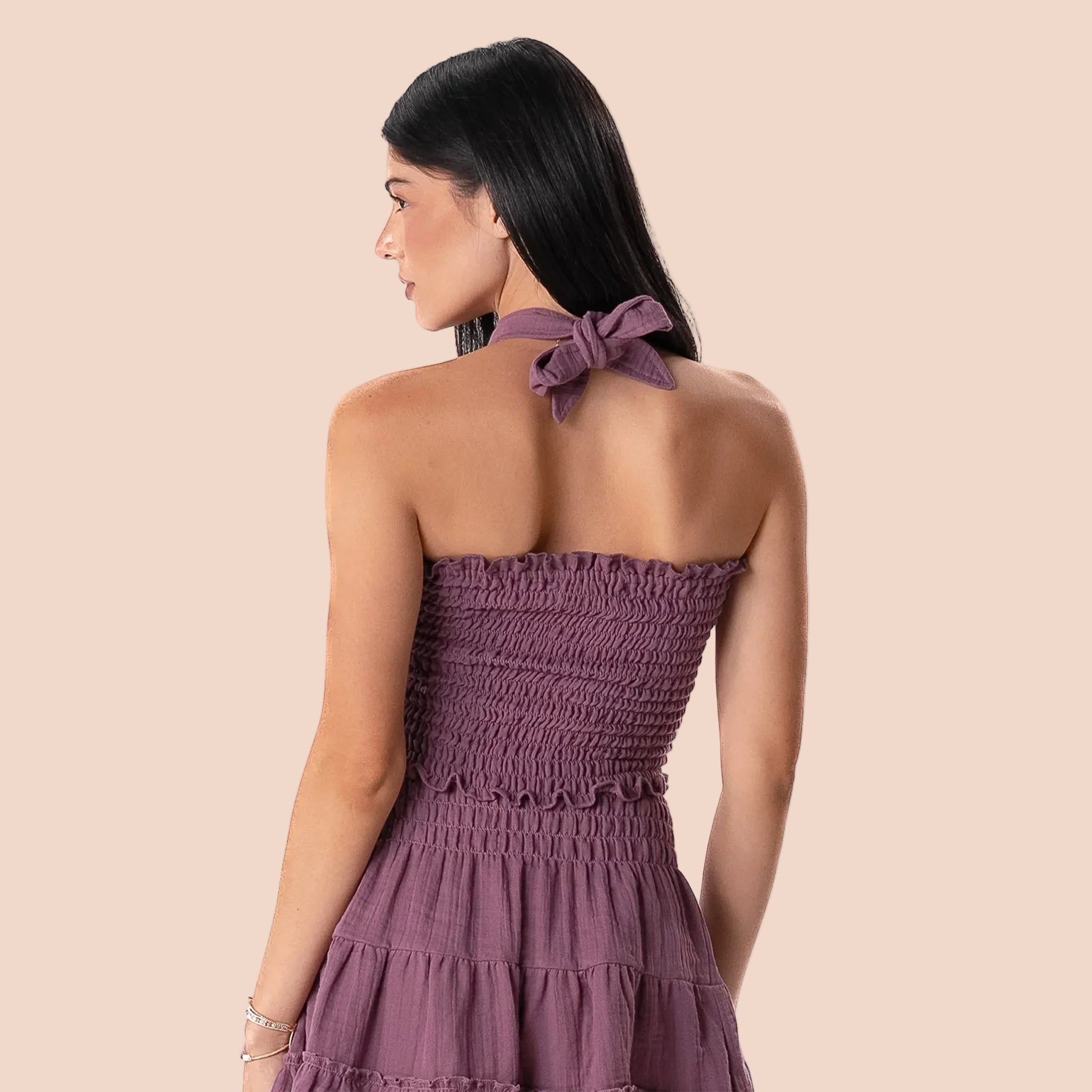 Woman wearing a purple strapless dress with a bow detail on a white background